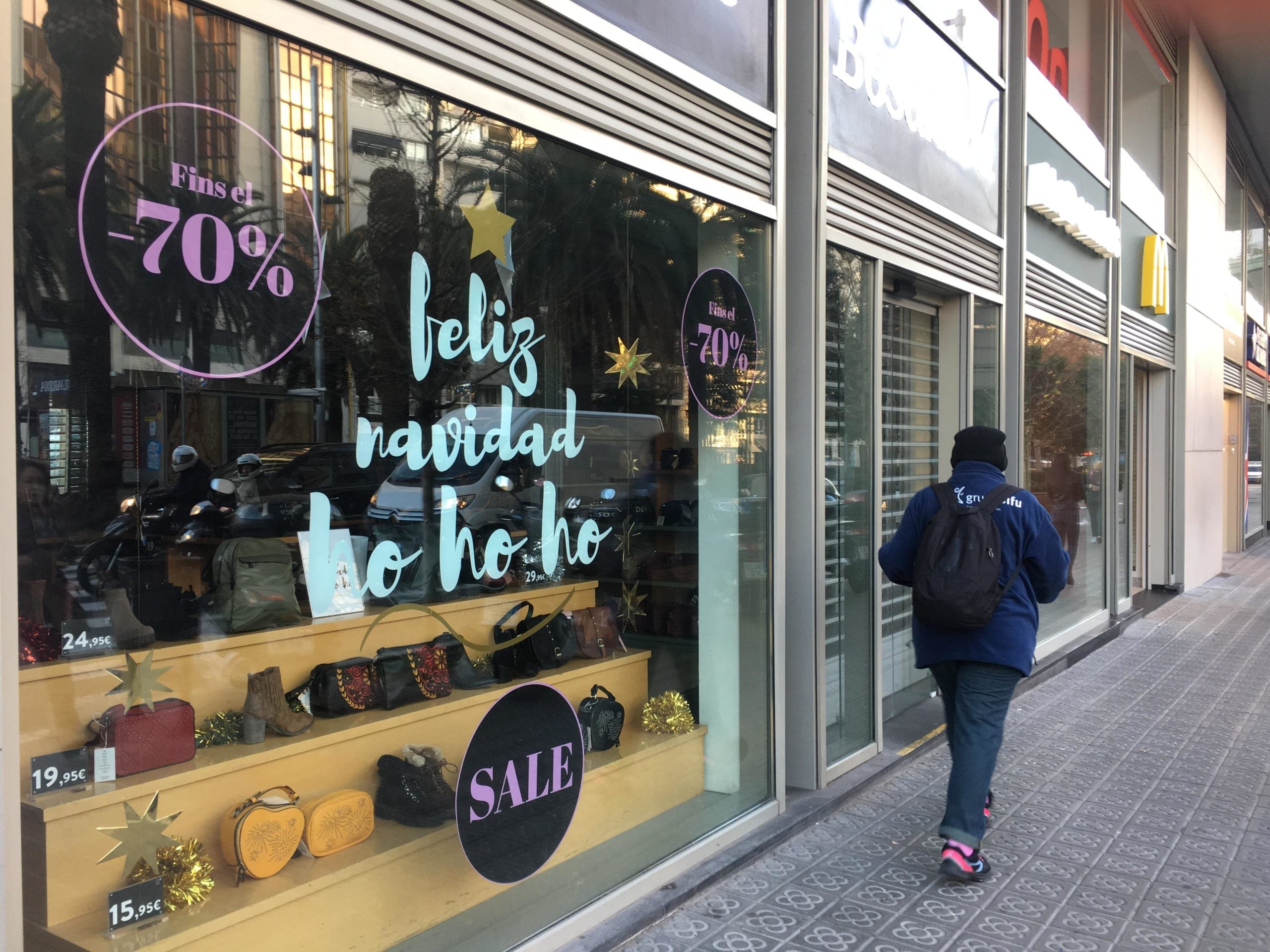 Un aparador on conviuen els cartells de la campanya de Nadal amb grans descomptes de rebaixes, a l'avinguda Josep Tarradellas / S.B.