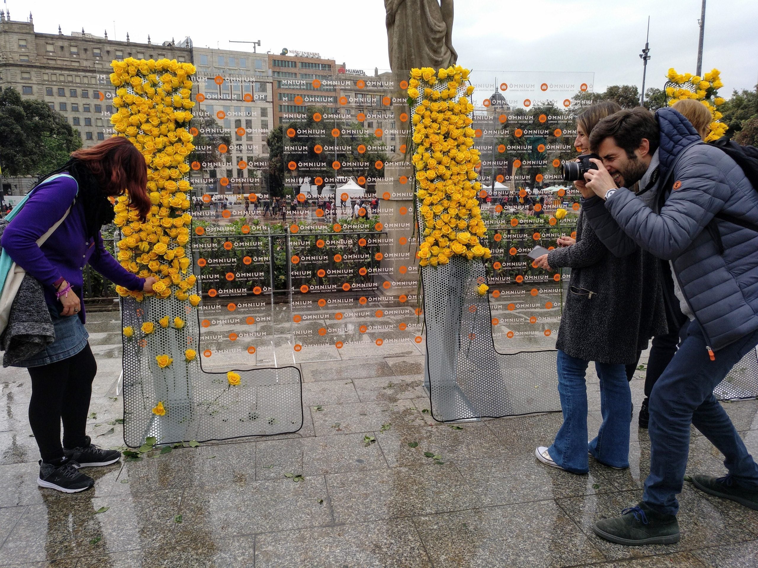 Una noia es fa fotografiar col·locant una rosa a la instal·lació d'Òmnium Cultural / MMP