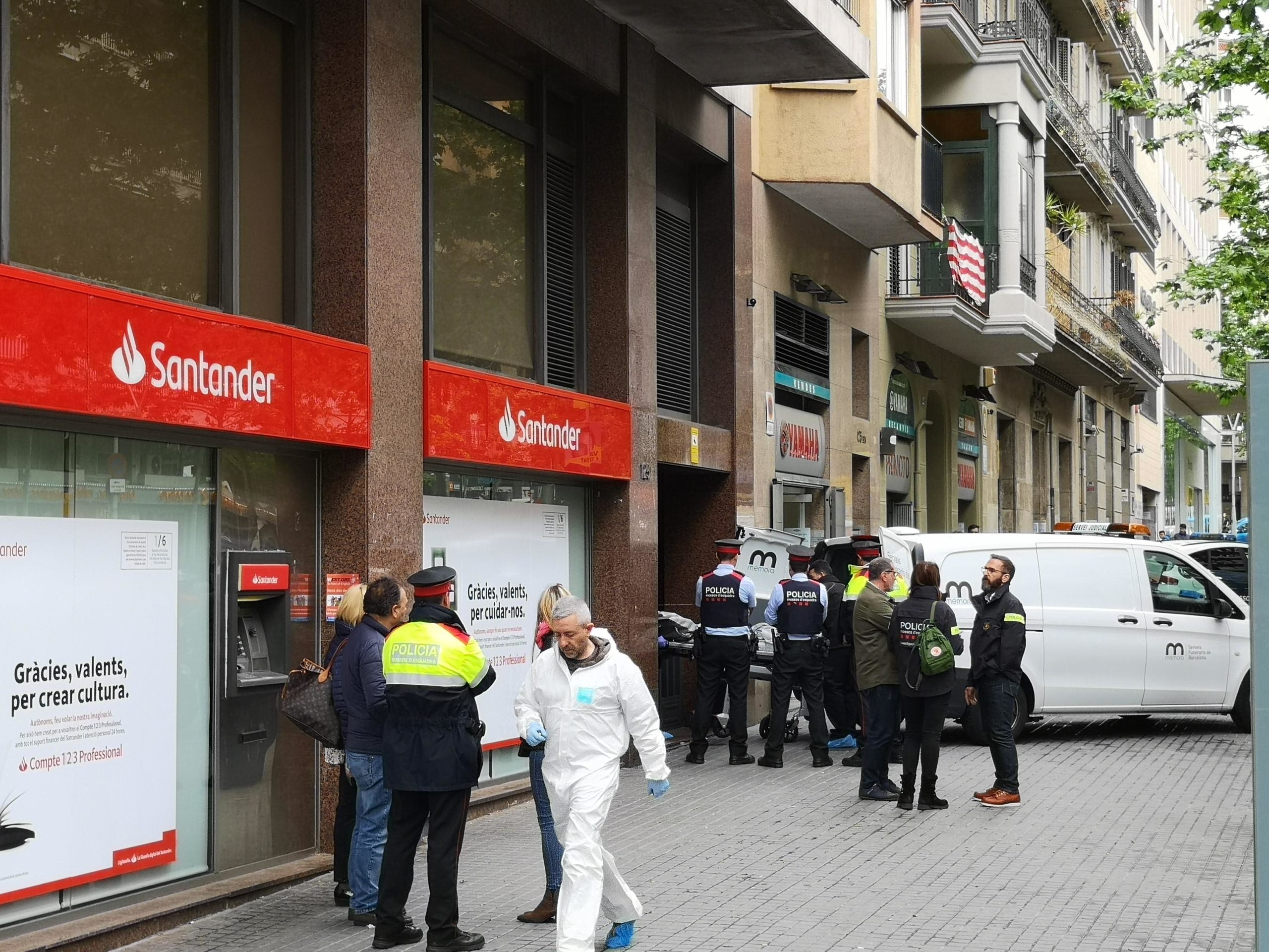 Agents de policia davant del lloc dels fets mentre els serveis funeraris s'enduen el cadàver de l'home que ha mort a trets al carrer Urgell / D.C.