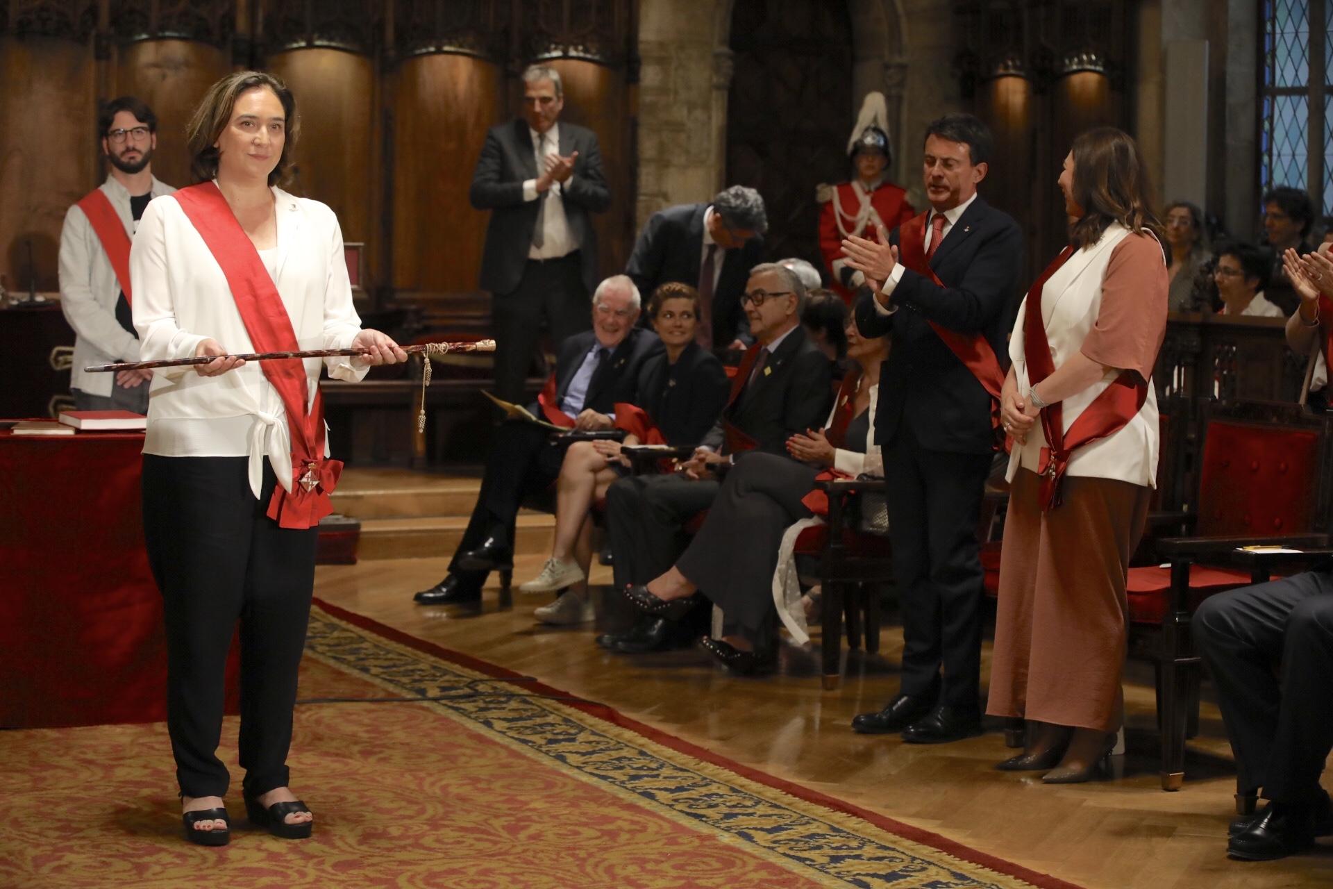 Ada Colau amb la vara d'alcaldessa, amb Ernest Maragall i Manuel Valls de fons / Jordi Play