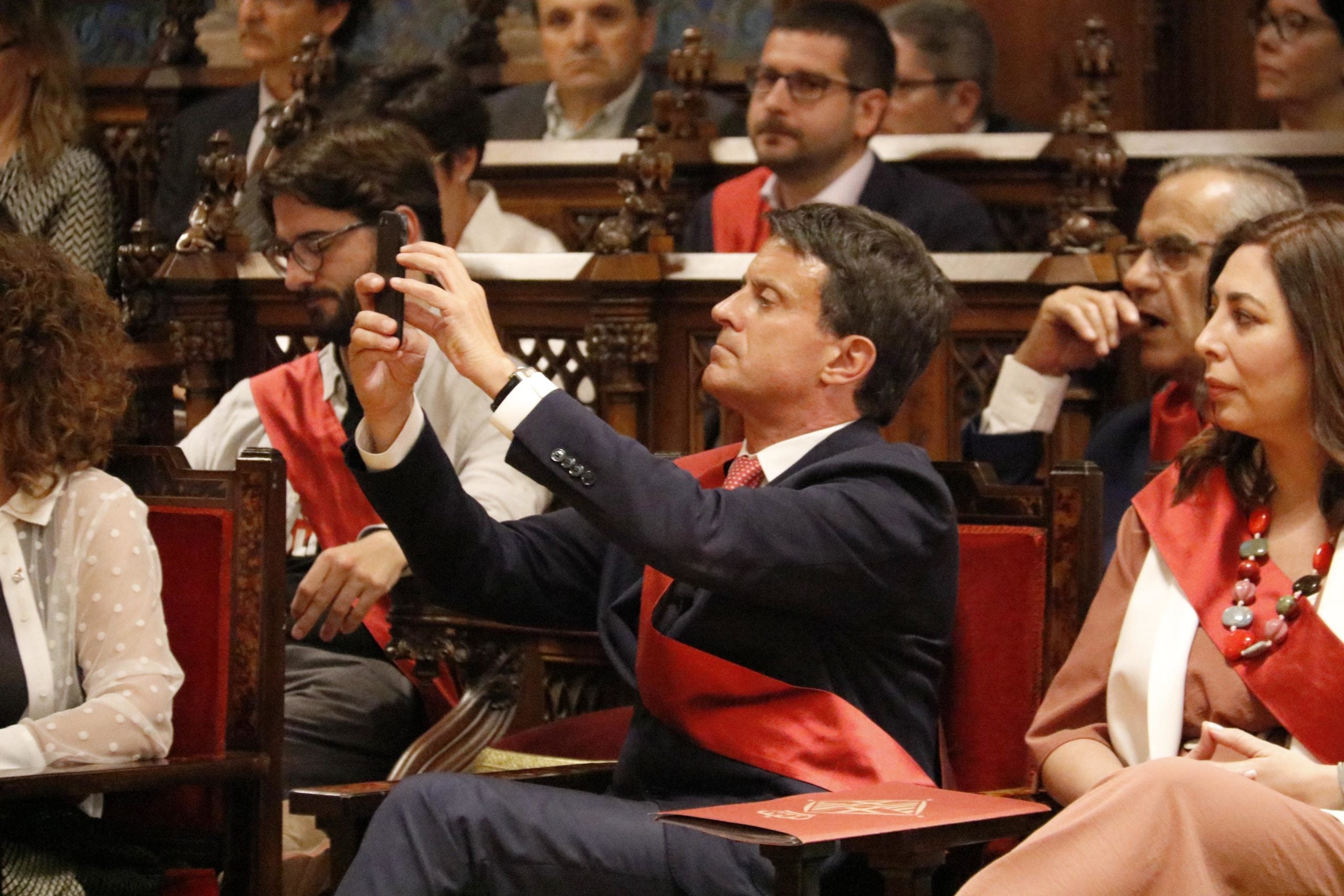 Manuel Valls fent una fotografia amb el telèfon mòbil durant el discurs d'investidura d'Ada Colau / ACN