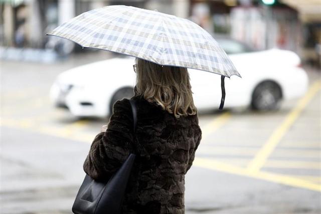 Una dona es protegeix de la pluja | Europa Press