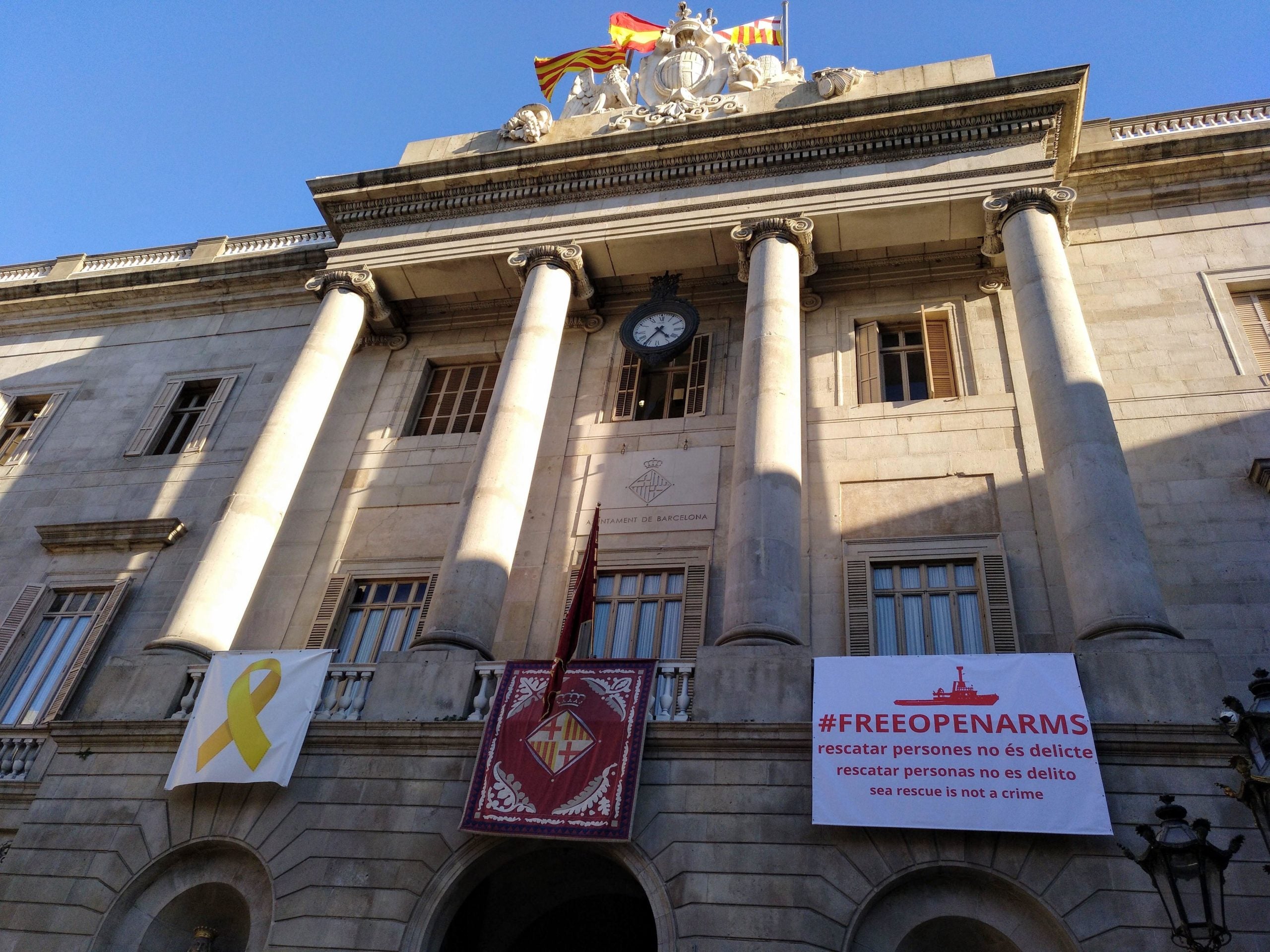 Llaç groc, penó de Santa Eulàlia i pancarta de suport a 'Open Arms' a la façana de l'Ajuntament de Barcelona, al febrer / MMP