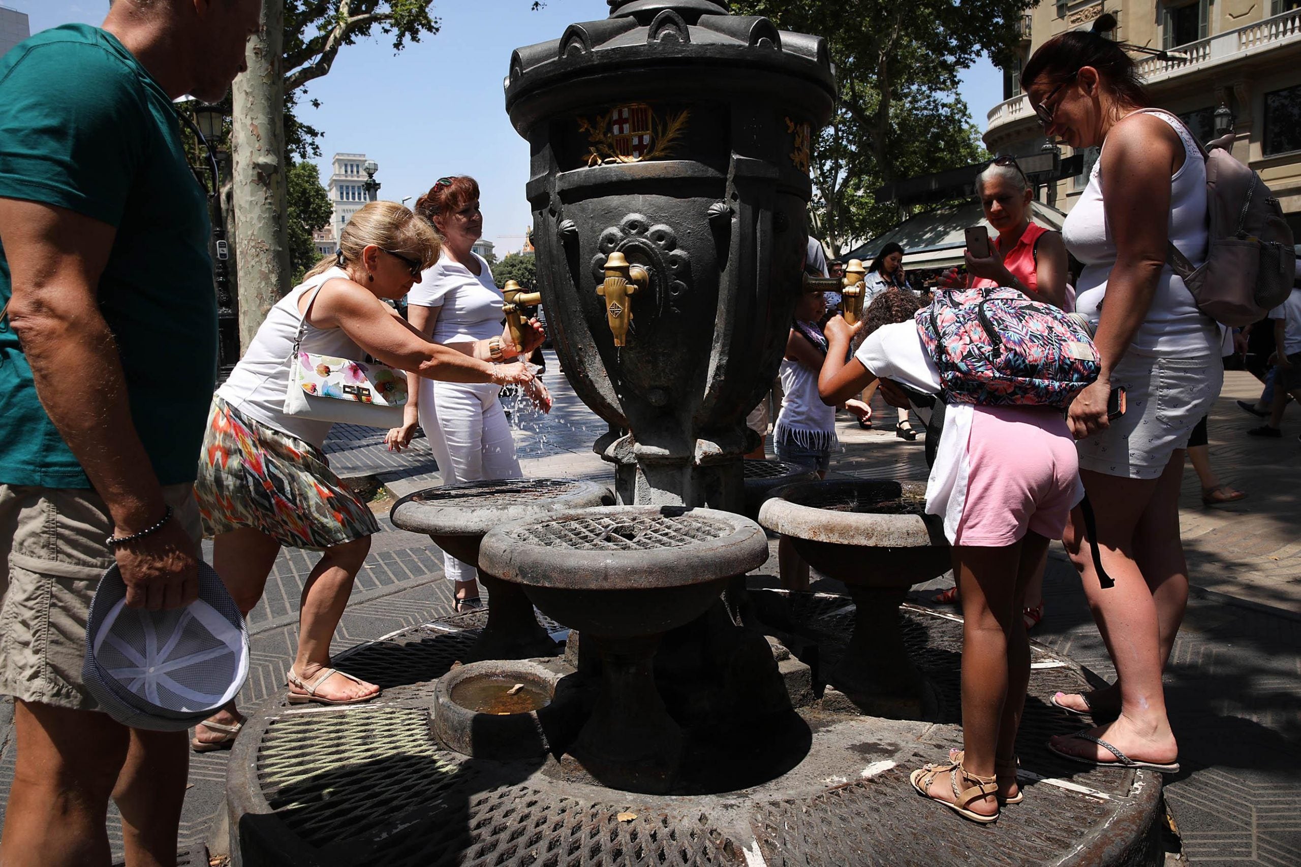 Turistes bebent aigua a la font de Canaletes de la Rambla, en plena on