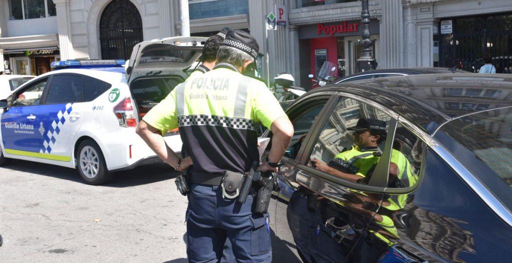 Dos agents de la Guàrdia Urbana aturen un vehicle VTC, en una imatge del juny passat | Ajuntament de Barcelona