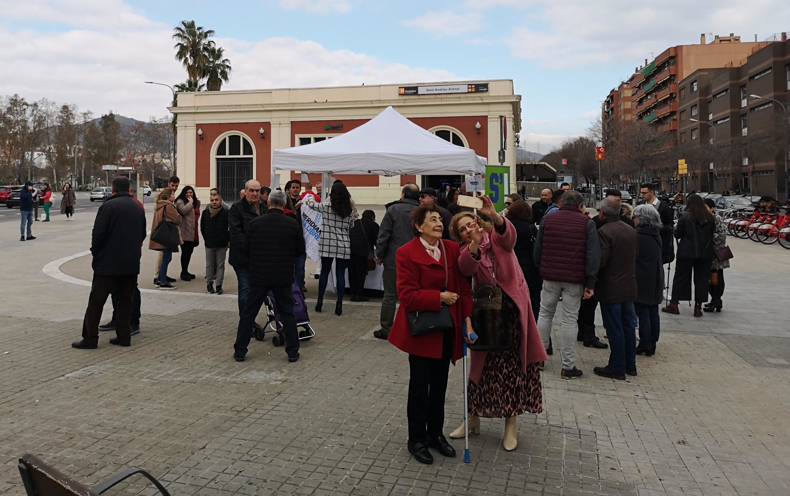 Dues dones es fan una foto al costat de la carpa que recull signatures contra el tall de la Meridiana / D.C.