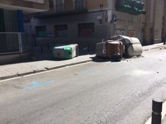 Contenidors tombats en un carrer d'accés a l'edifici okupat al Raval / Cedida