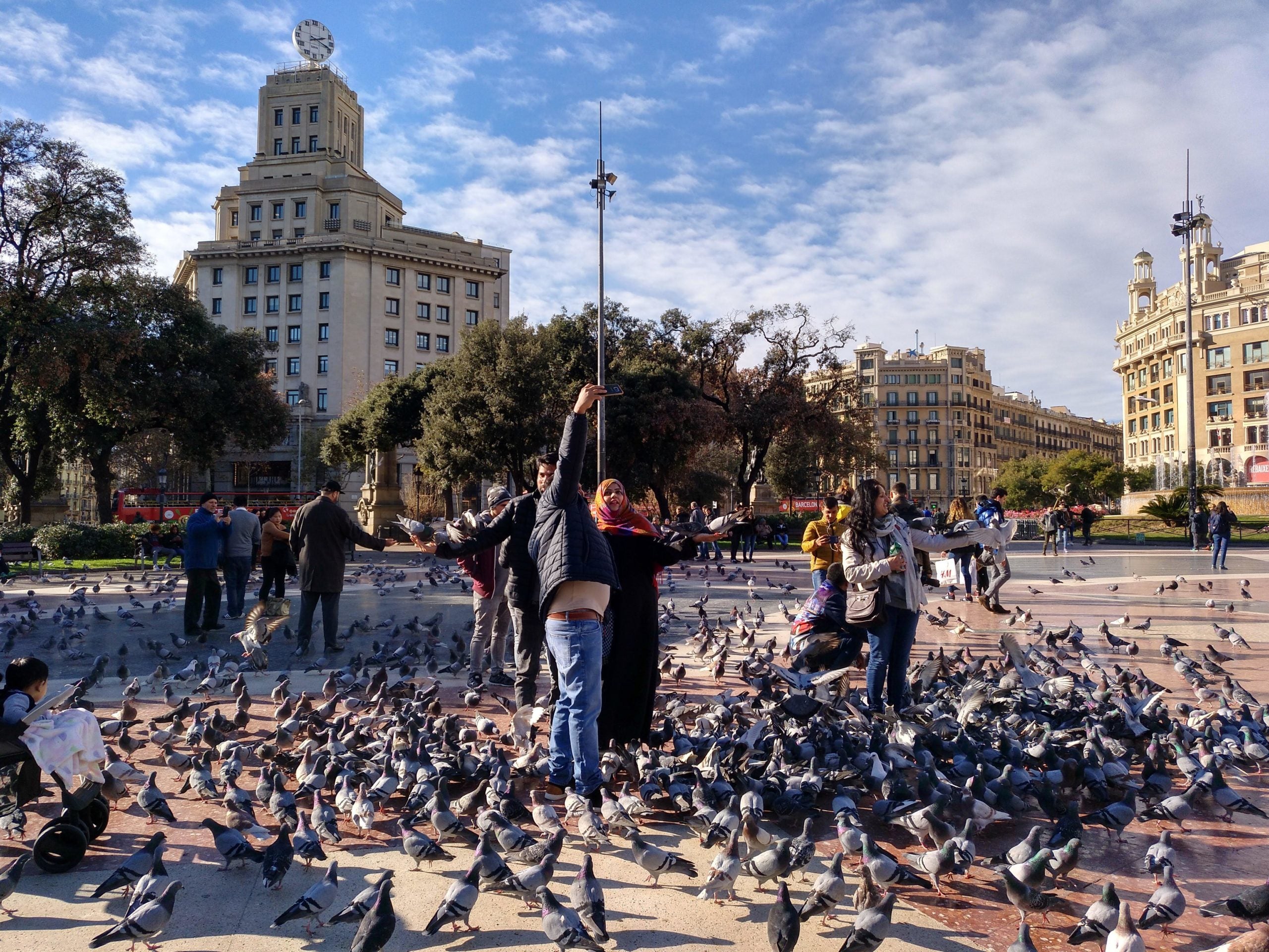 Un grup de turistes es fa fotos amb els coloms a plaça Catalunya, en una imatge d'arxiu / Meritxell M. Pauné