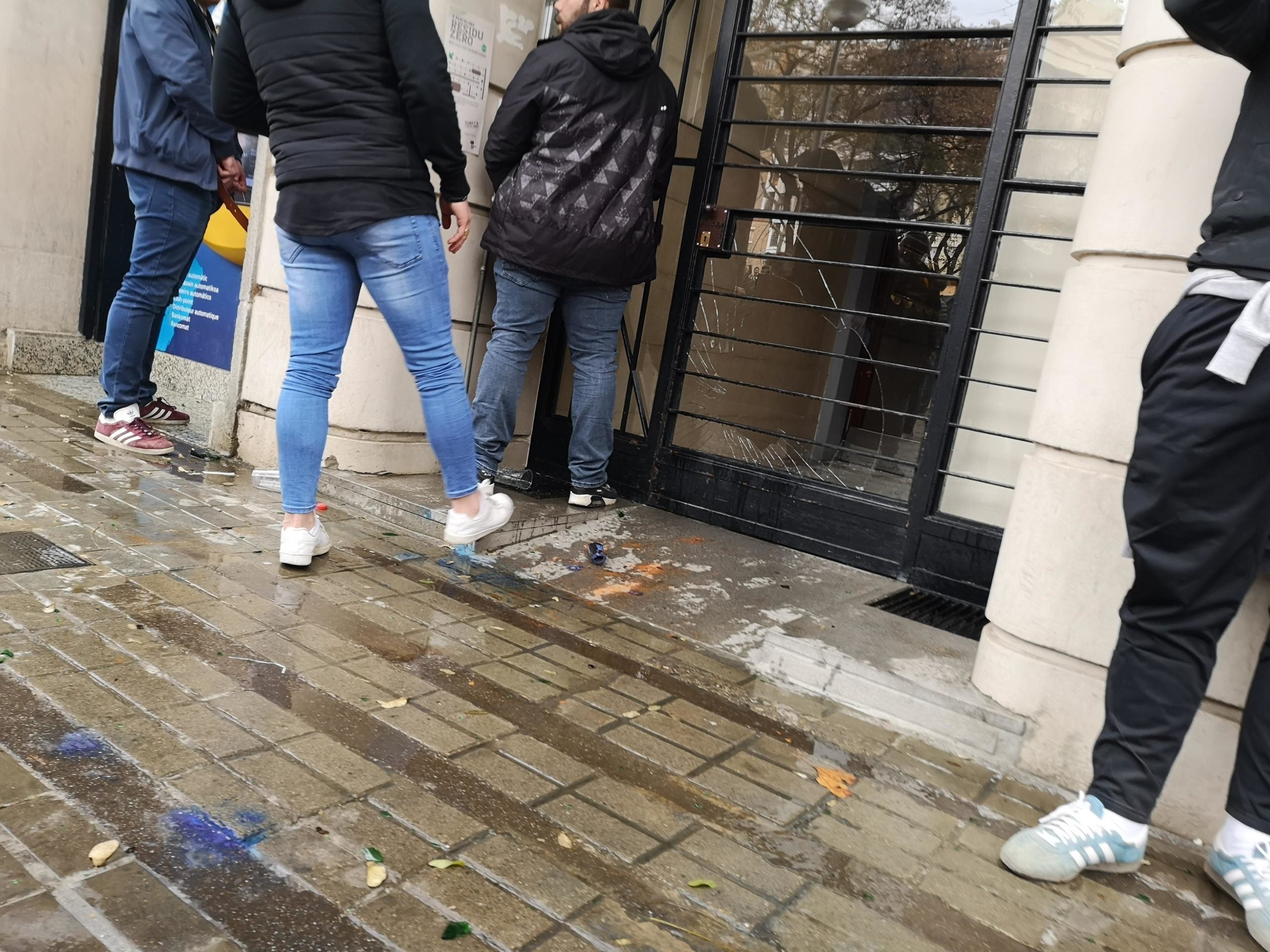 La porta de l'edifici amb el vindre trencat mentre una persona orina a la pla&ccedil;a Art&oacute;s. / D.C.