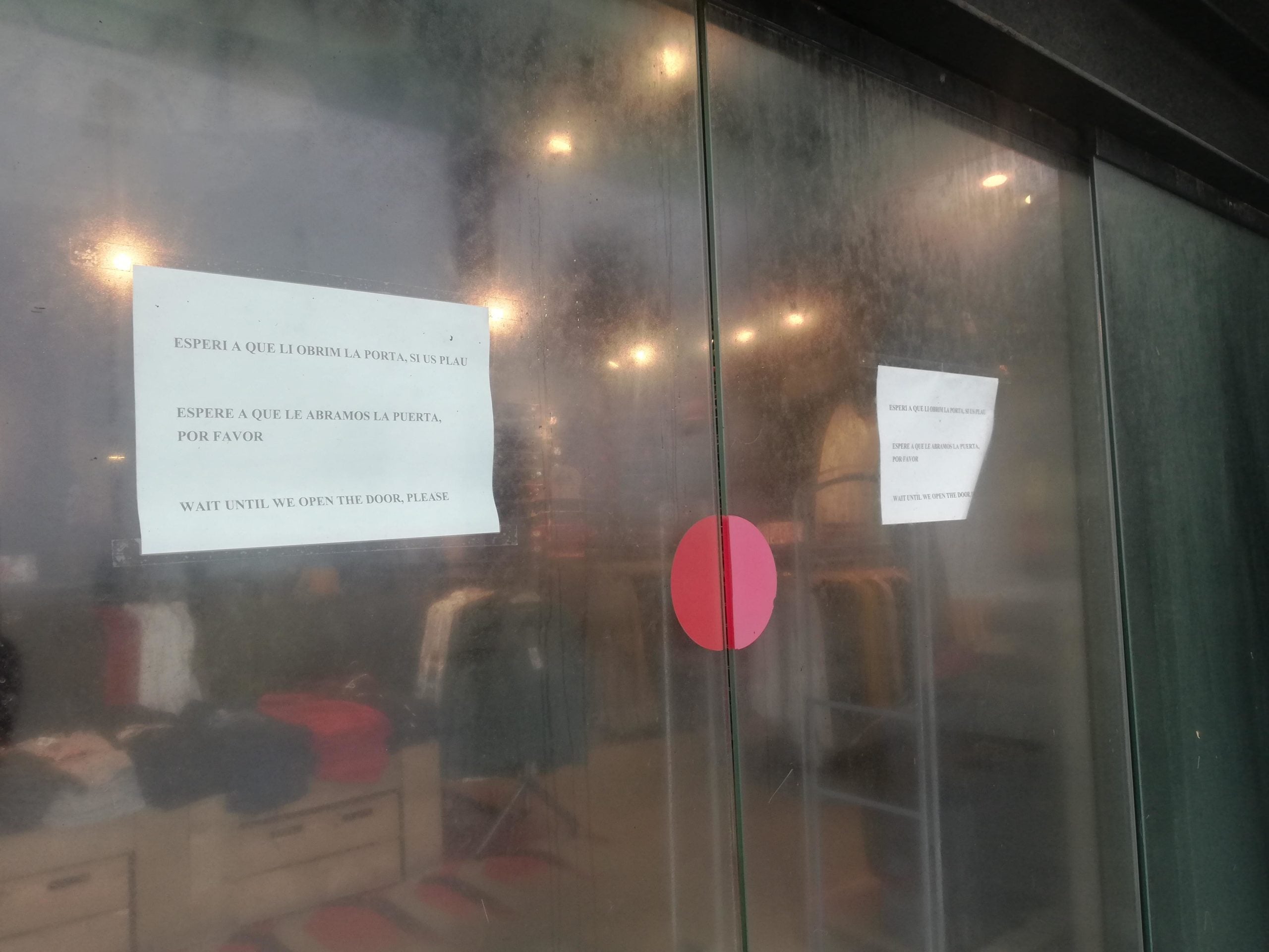 El cartell que demana als clients que esperin abans d'accedir a la botiga / A. L.
