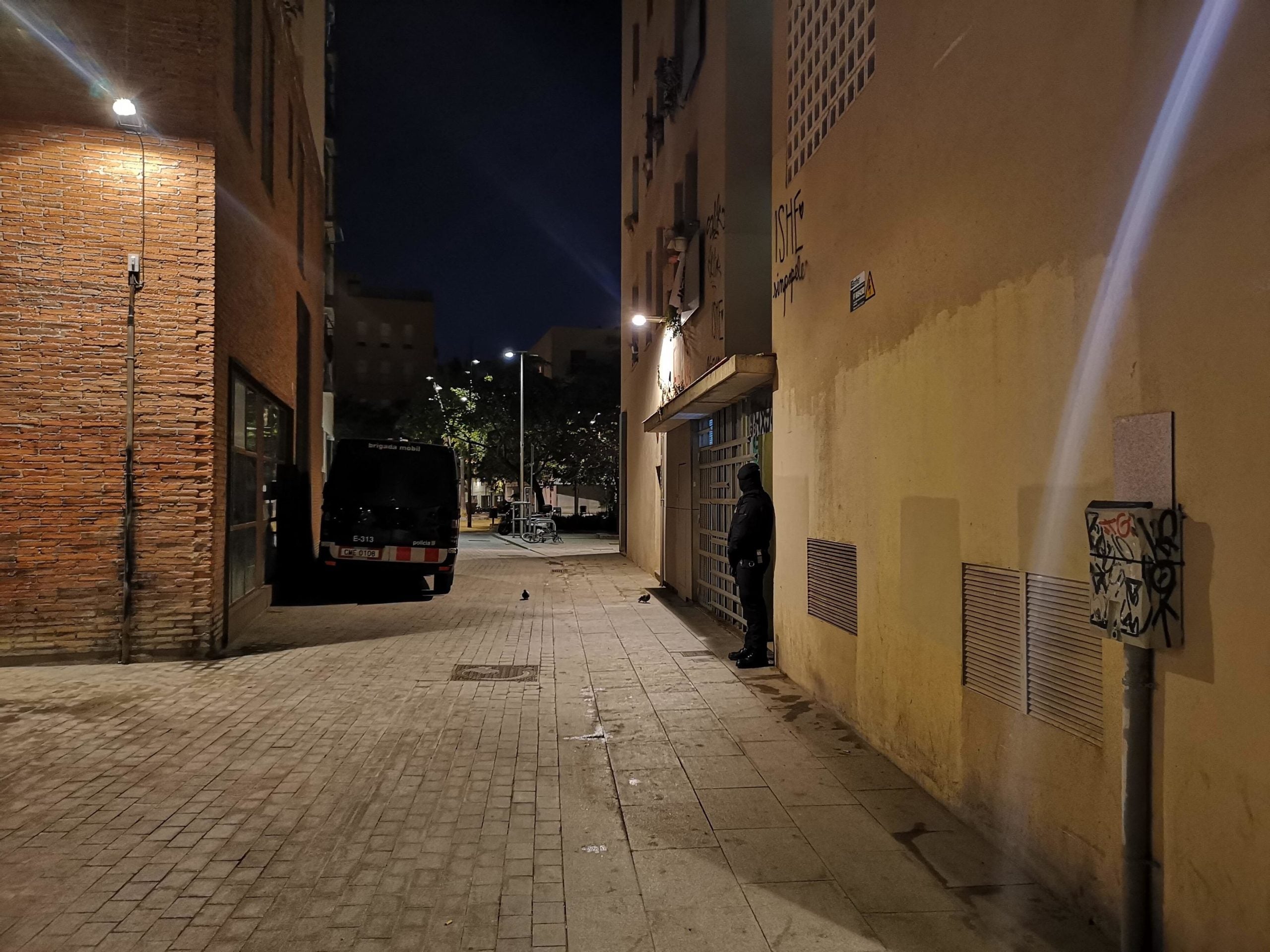 Un agent dels Mossos d'Esquadra custodia la porta d'un dels edificis de Barcelona on s'està fent un dels escorcolls de l'operació antiterrorista / DAVID COBO