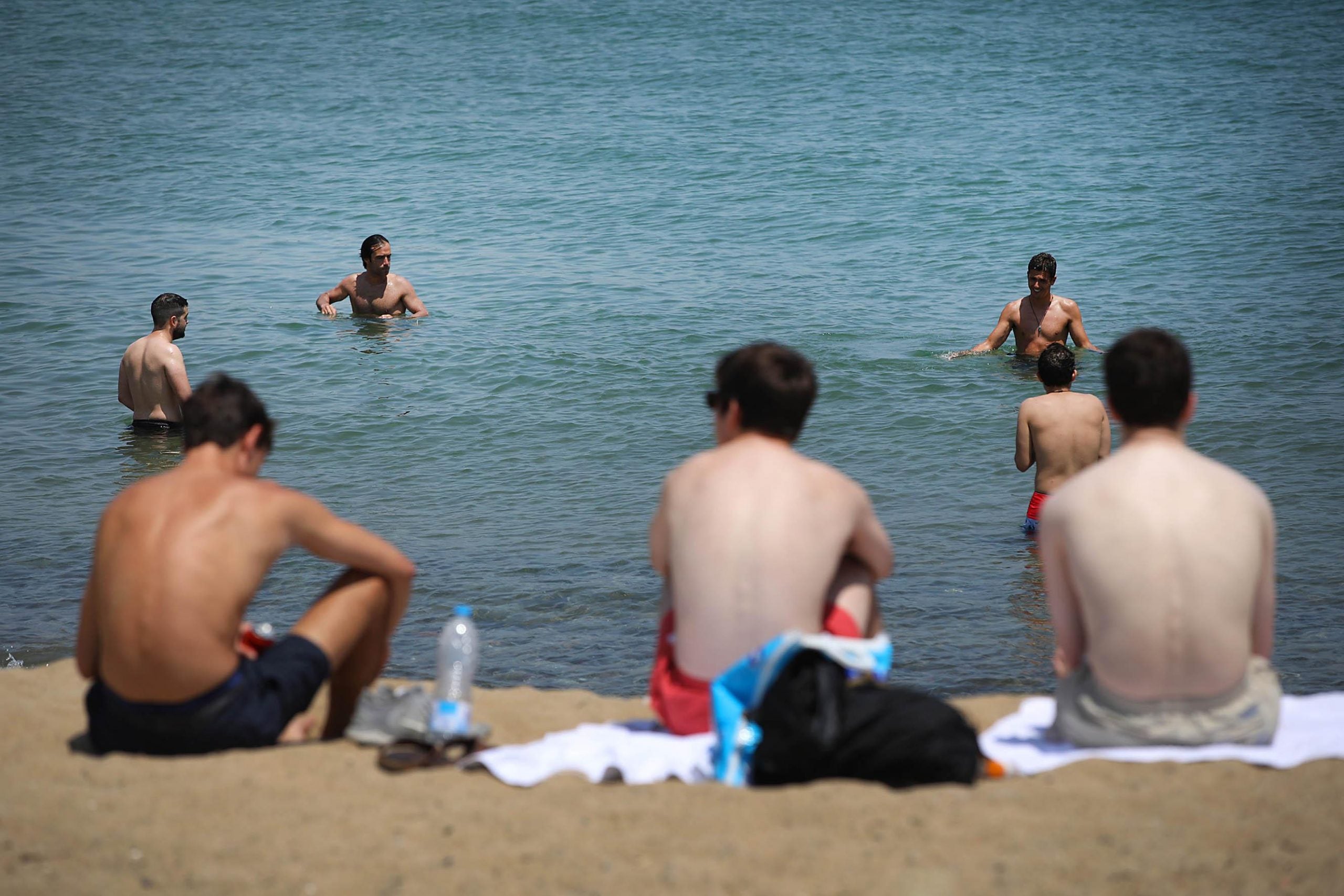 Usuaris de la platja de Barcelona banyant-se i prenent el sol, en plen