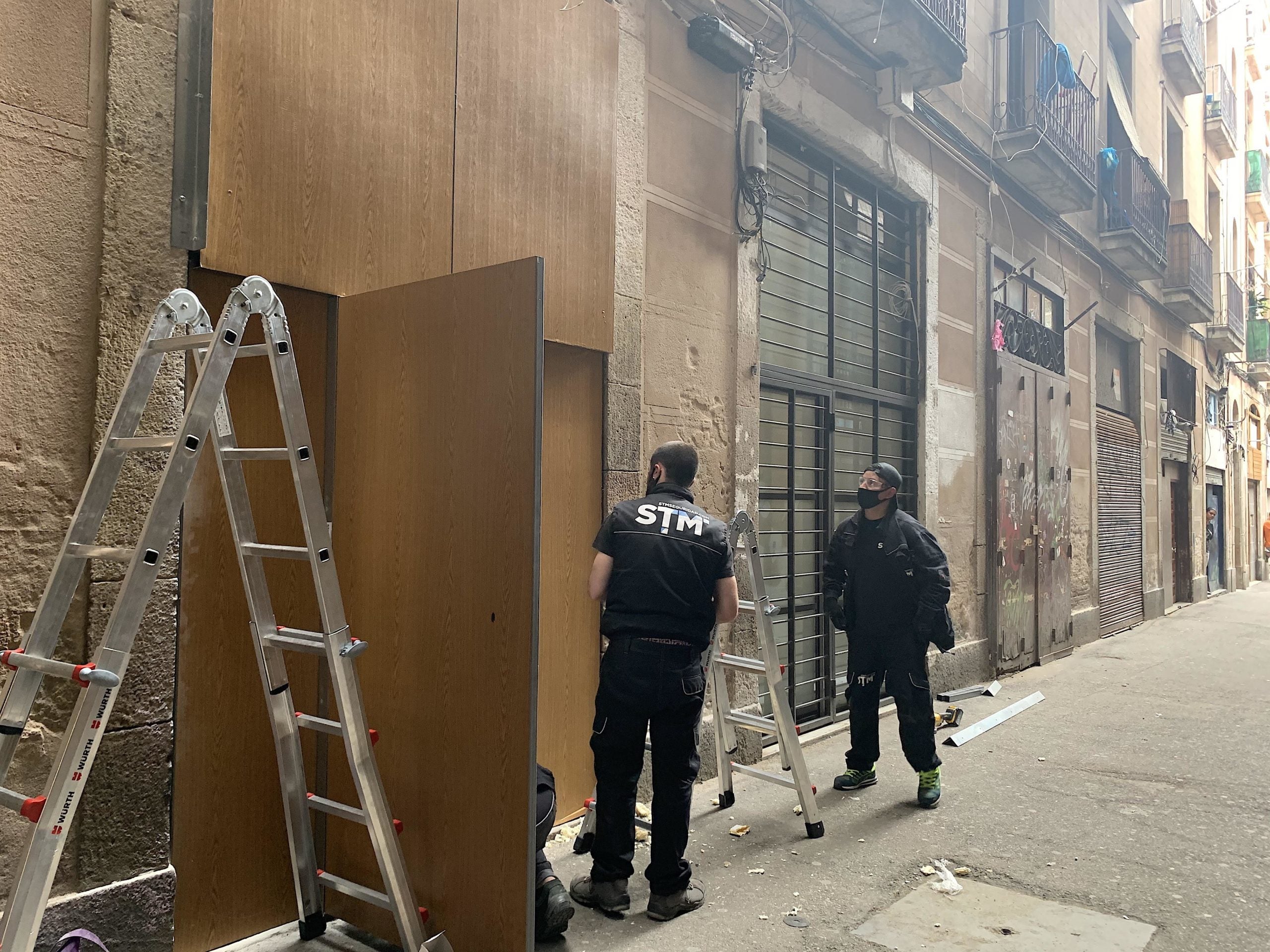 Operaris posant una porta antiokupes a l'accés de la finca del número 99 del carrer Hospital, on han foragitat un grup de traficants / S.B.