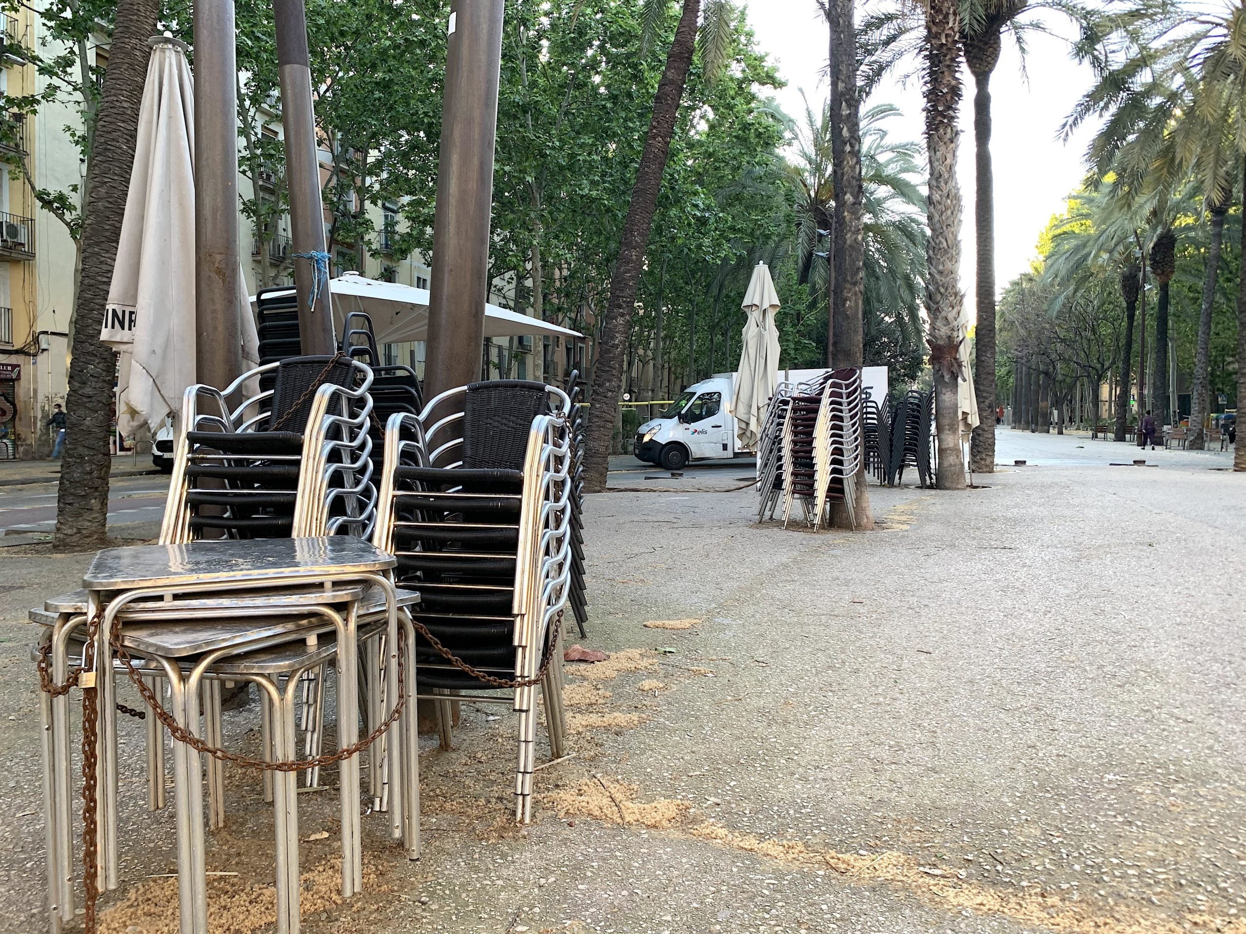 Taules i cadires de terrasses de bars de la Rambla del Raval, recollides i lligades amb una cadena i un cadenat durant el confinament pel coronavirus / S.B.