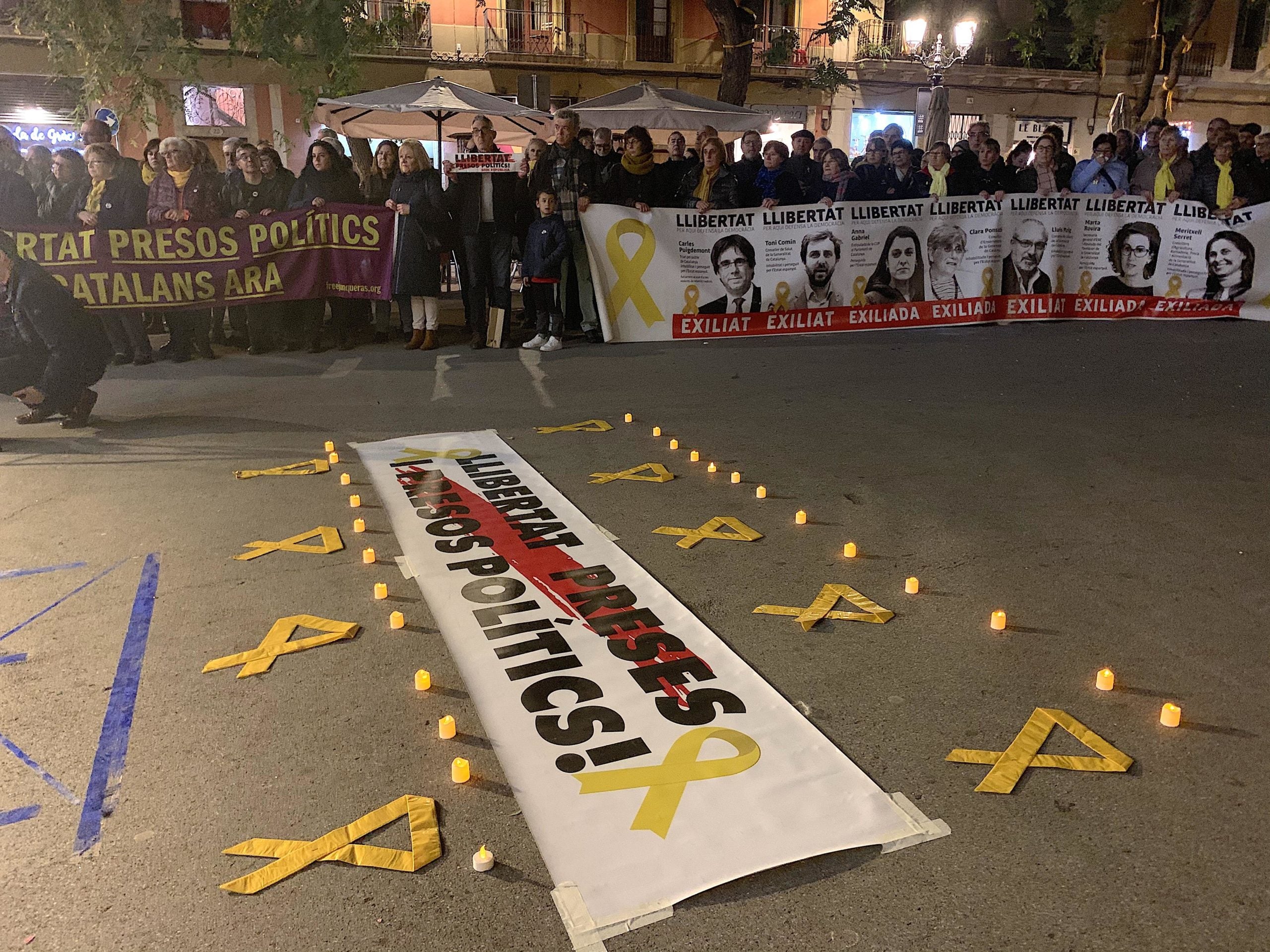 La concentració pels presos i els exiliats de la plaça de la Vila de Gràcia, amb rètol i les espelmes a terra / S.B.