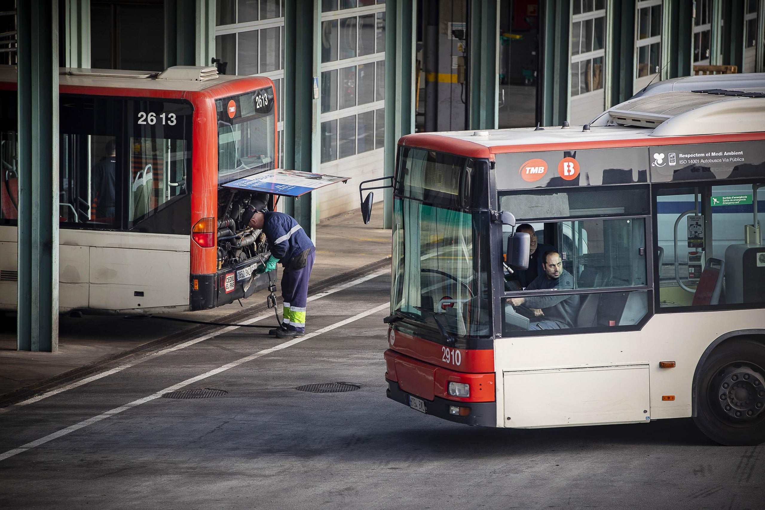 Un conductor de bus entra a les cotxeres d'Horta mentre un altre treballador revisa un vehicle, en imatge d'arxiu / Jordi Play