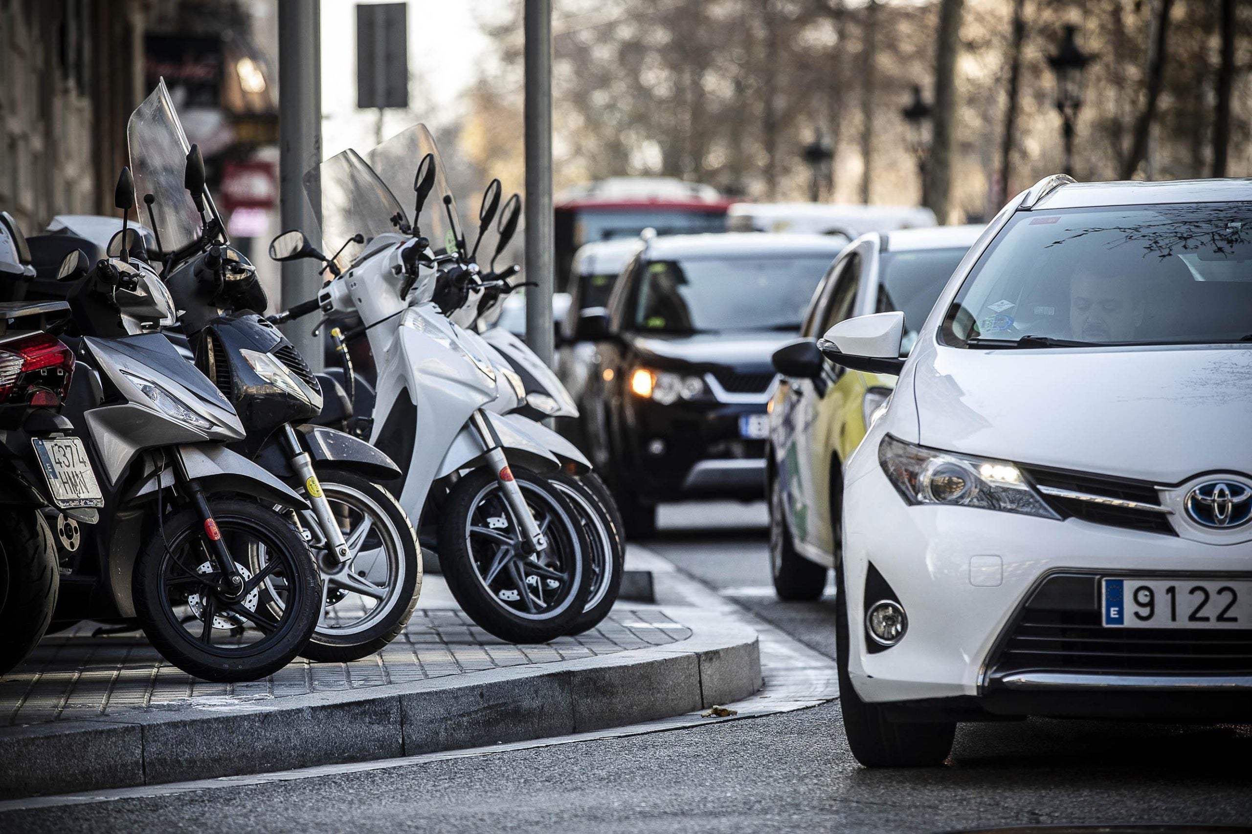 Motocicletes aparcades en una vorera i trànsit a Barcelona, en una imatge d'arxiu / Jordi Play