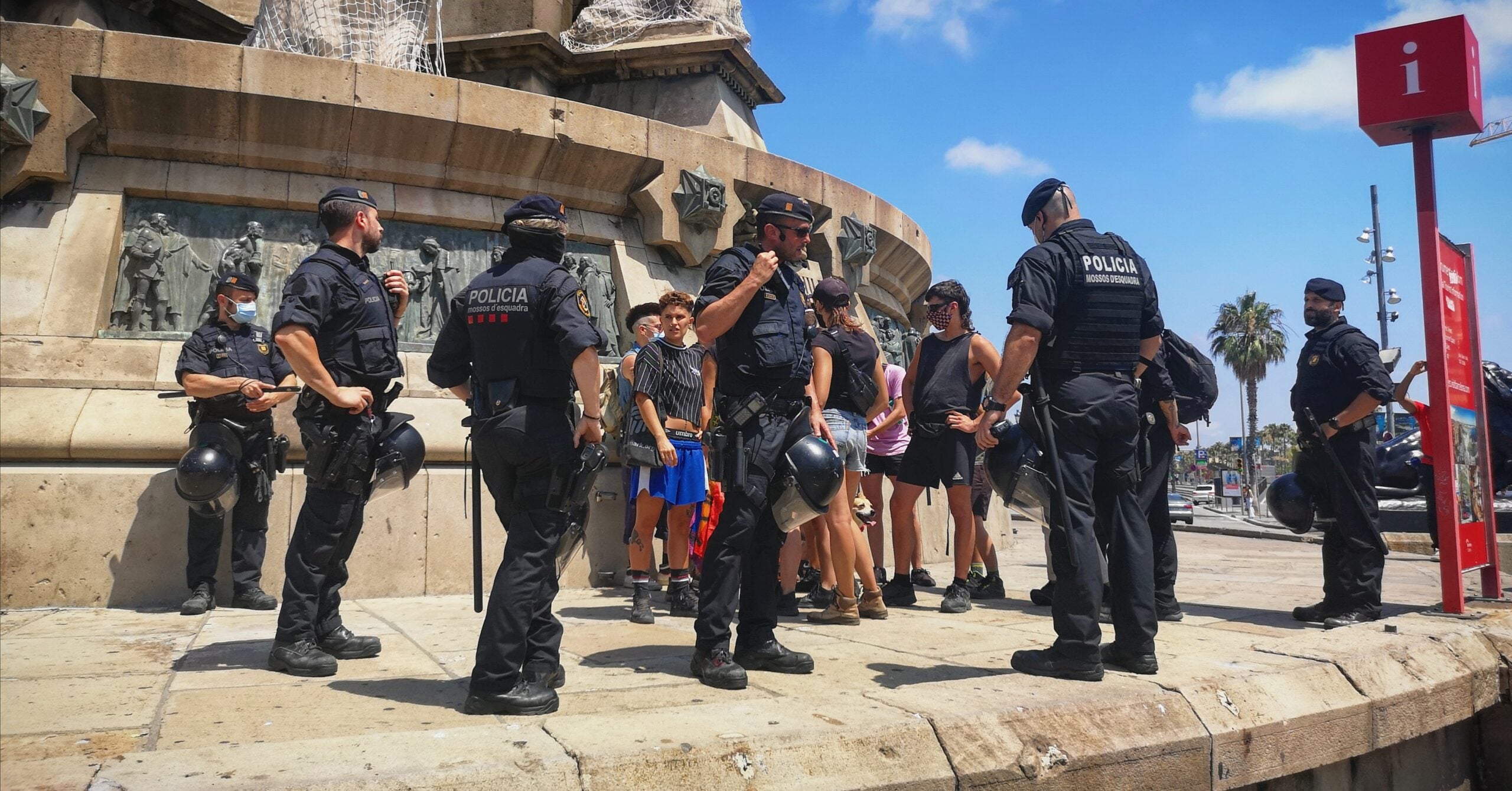 El grup de la bandera LGTBI, envoltat per policies a l'estàtua de Colom / D.C.