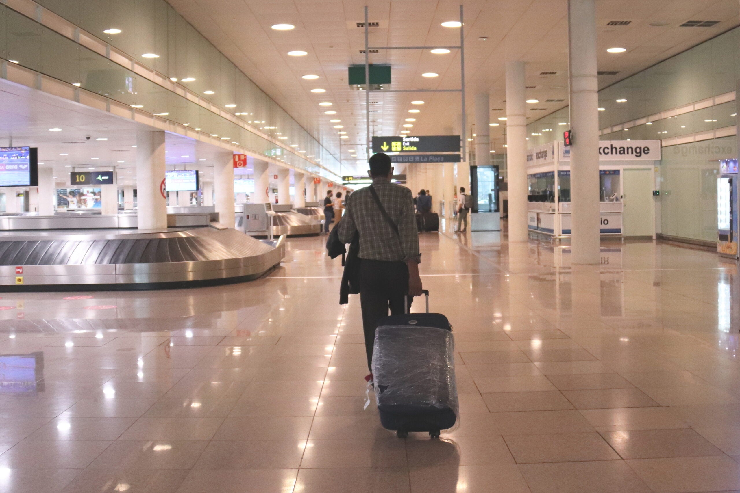 Un viatger caminant amb maletes a la zona d'arribades de la T1 a l'aeroport del Prat el dia 19 / ACN