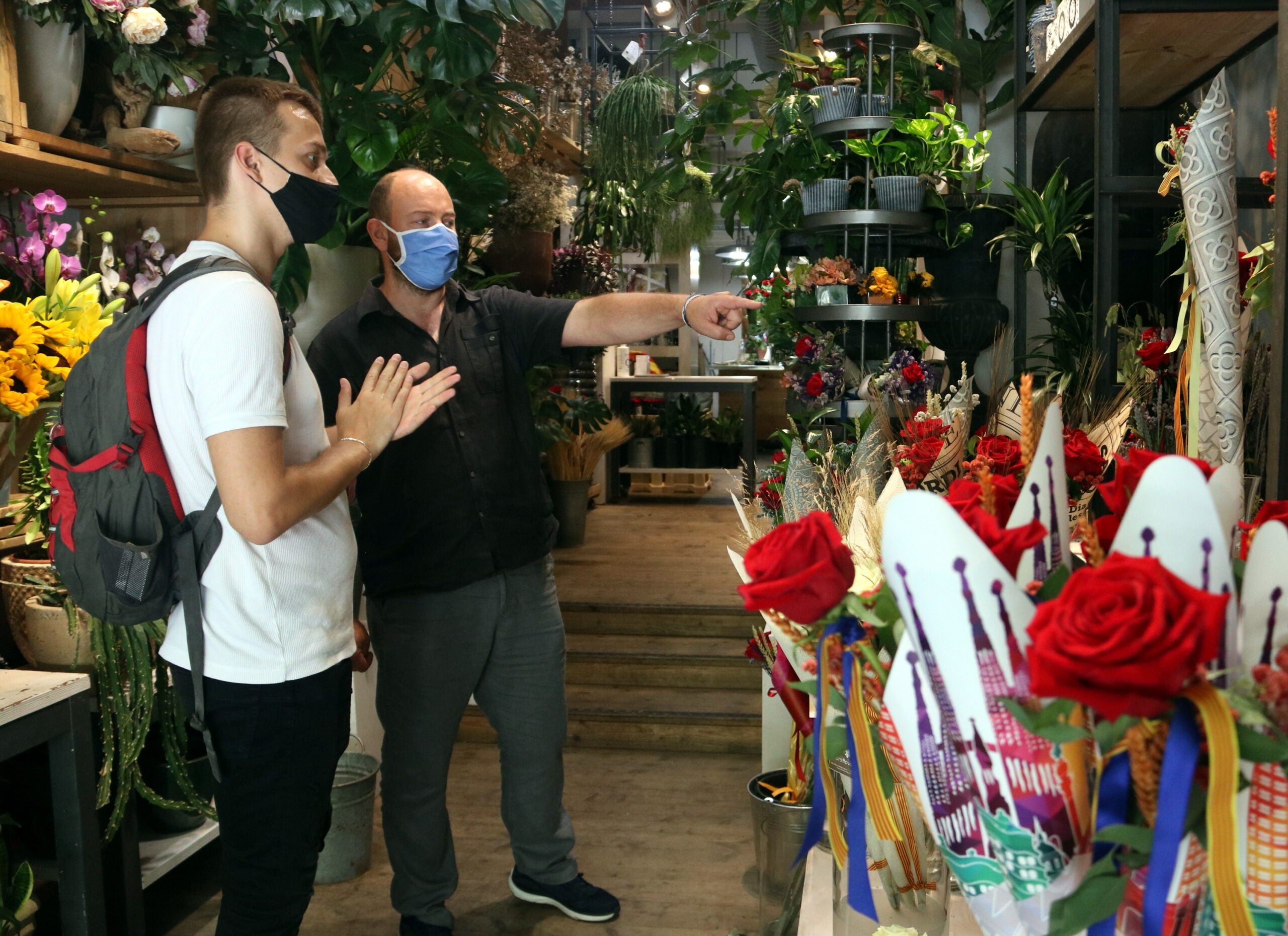 Un florista de l'Eixample aconsella un comprador de roses, que es frega les mans després de posar-se gel hidroalcohòlic / ACN - Pau Cortina