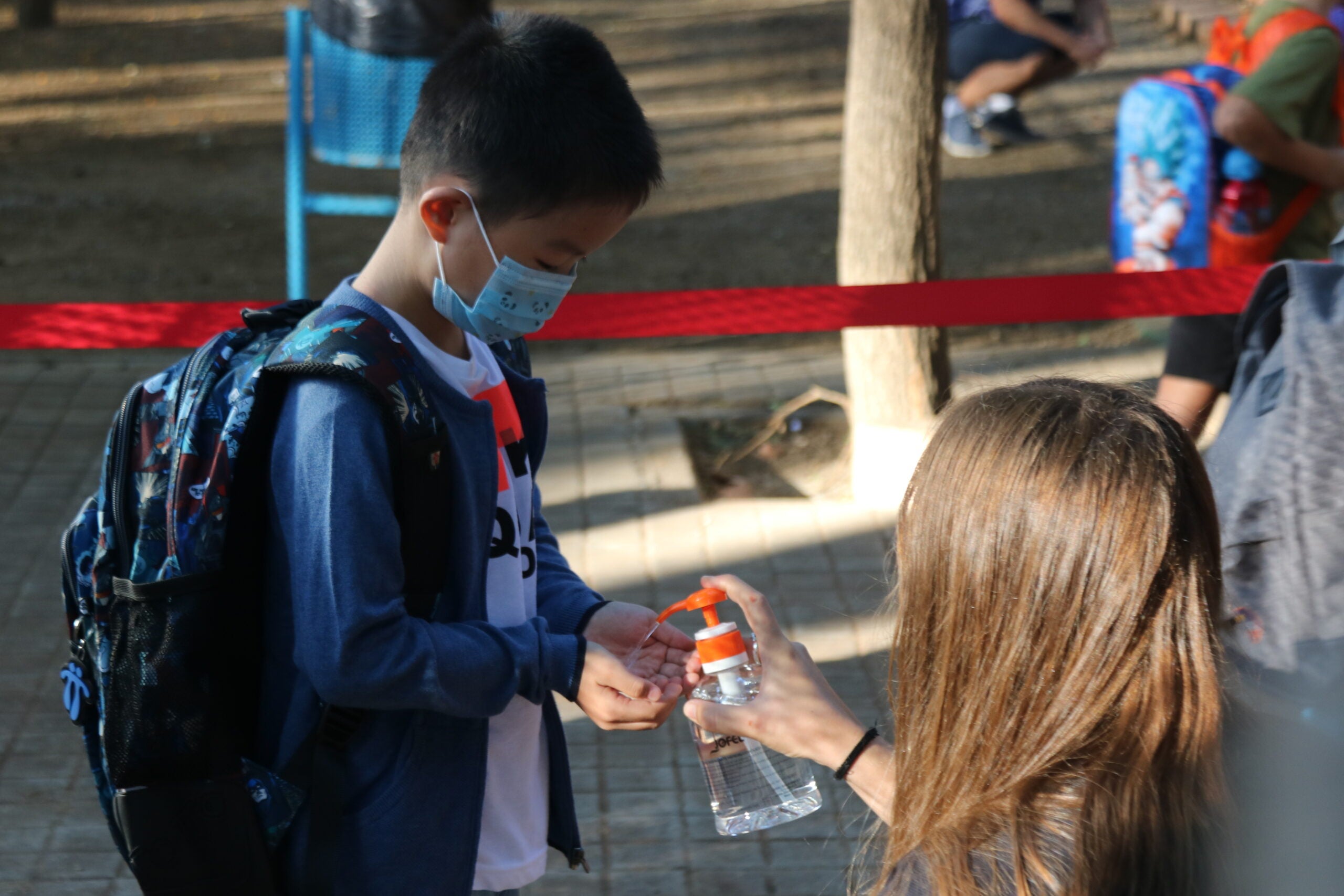 Un alumne de l'Escola Catalònia de Barcelona posant-se gel desinfectant a l'entrada del centre en el primer dia de classes / ACN