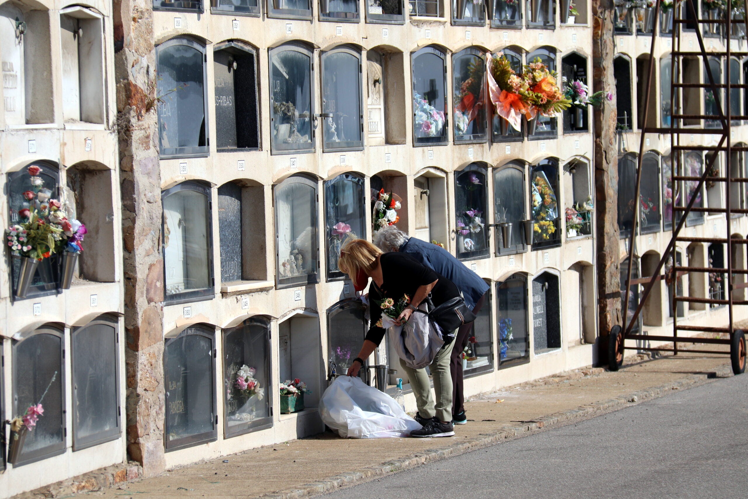 Dues dones dipositen flors en una tomba al cementiri de Montjuïc per Tots Sants, l'1 de novembre del 2020 / ACN