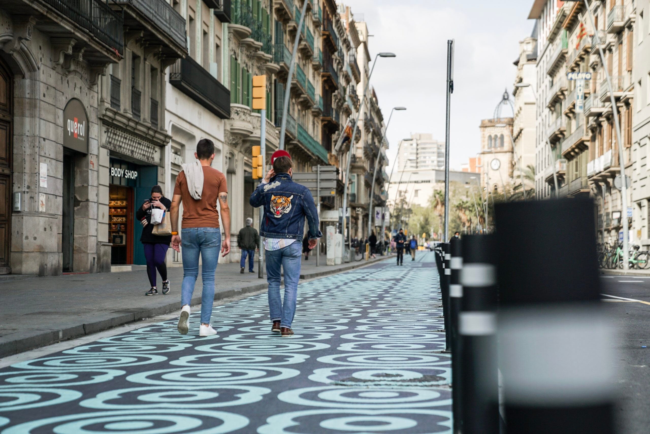 Dos homes caminant pel carrer Pelai, amb un nou espai per a vianants pintat amb panots blaus / ACN