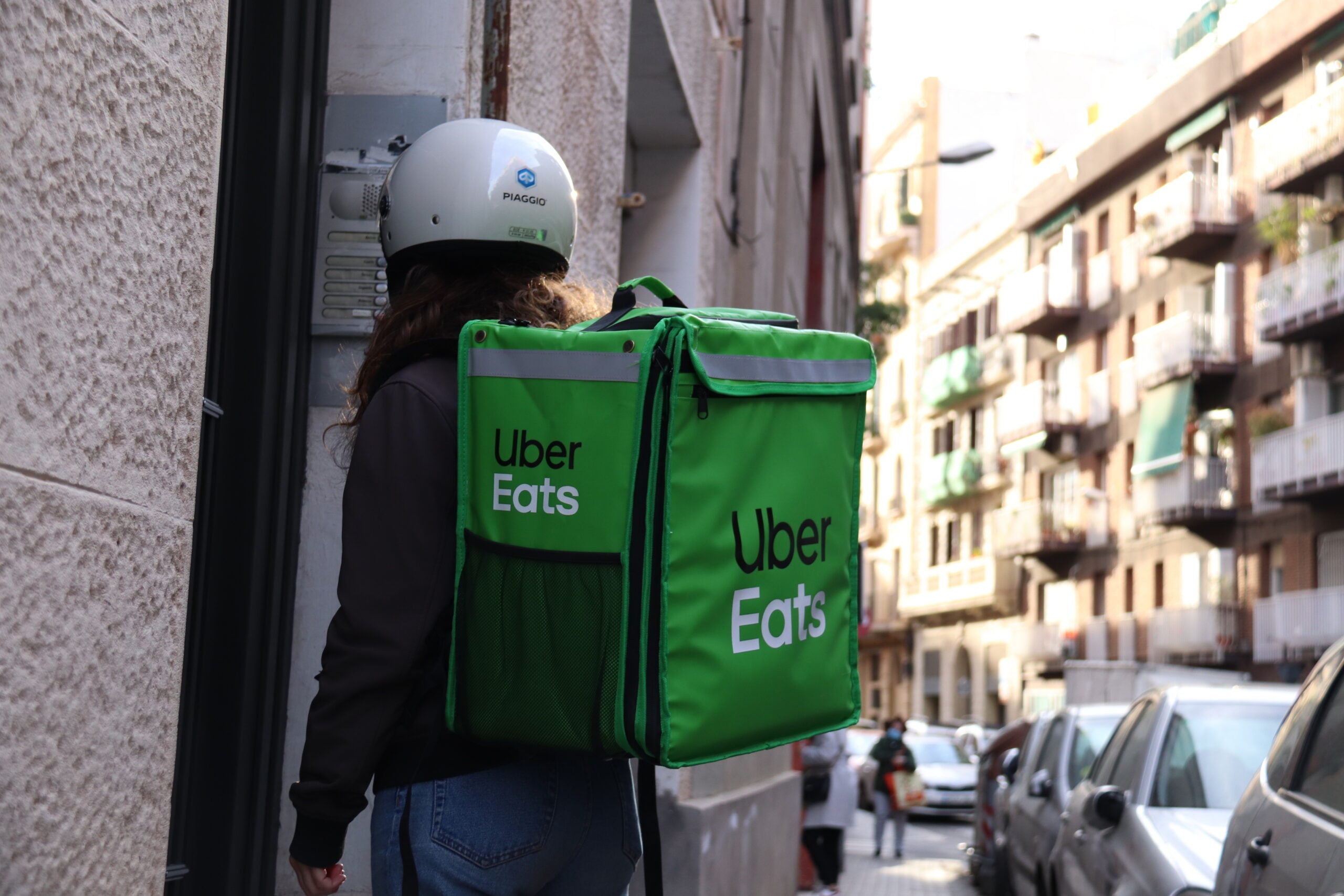 Una repartidora d'Uber Eats esperant per entrar a entregar una comanda a un domicili / ACN