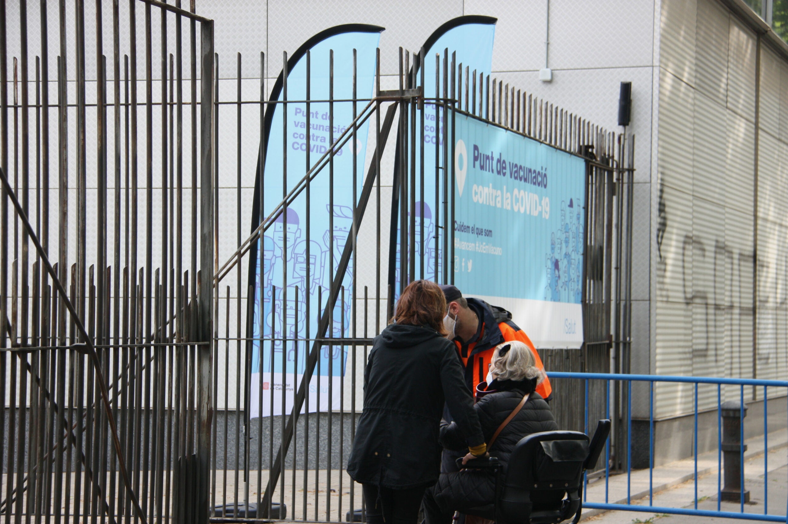 Un agent cívic ajudant a dues dones que entraven al punt de vacunació de la Fira de Barcelona / ACN