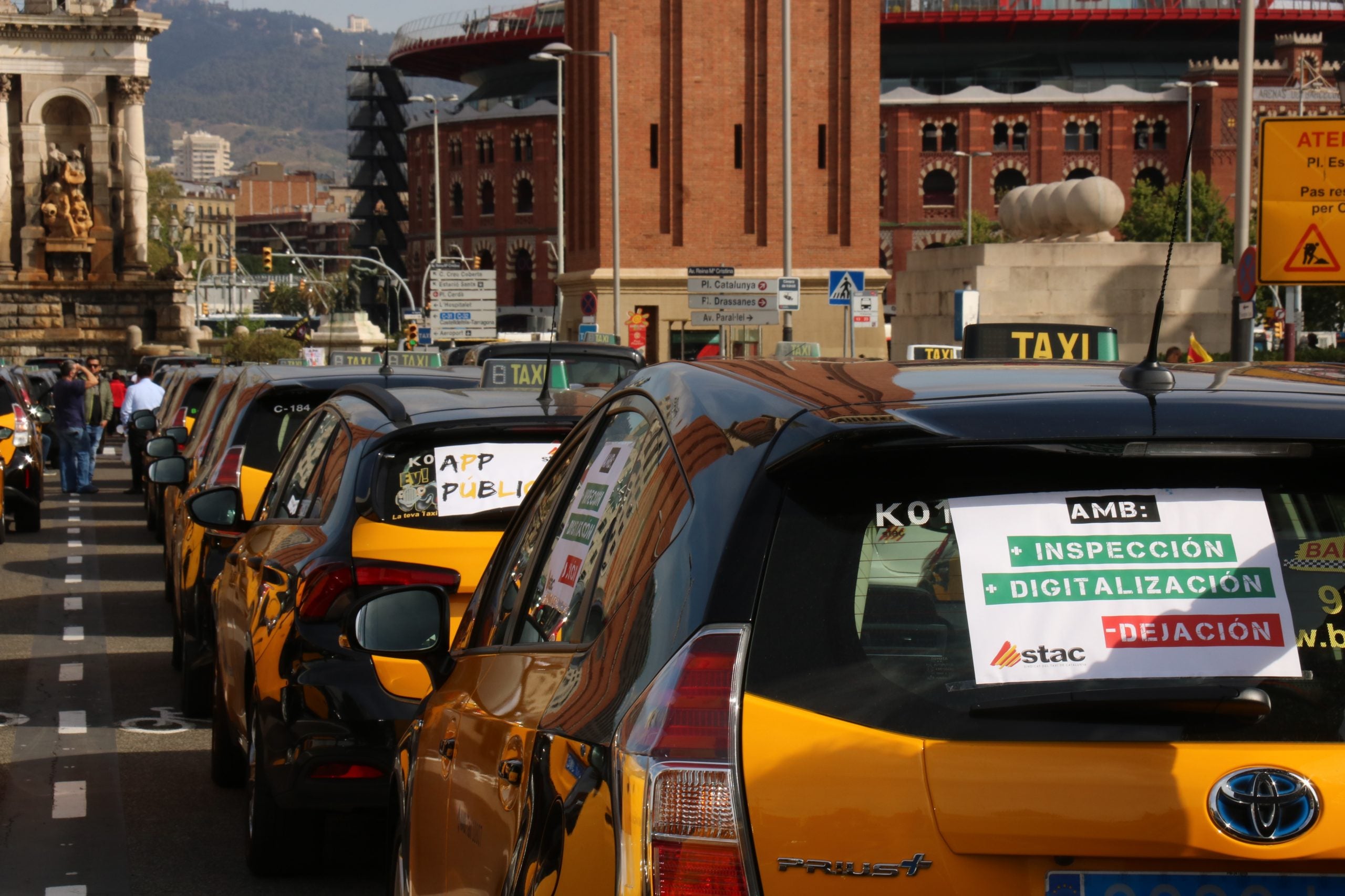 Dos taxis amb els cartells reivindicatius abans de començar la protesta a l'Avinguda Maria Cristina / ACN