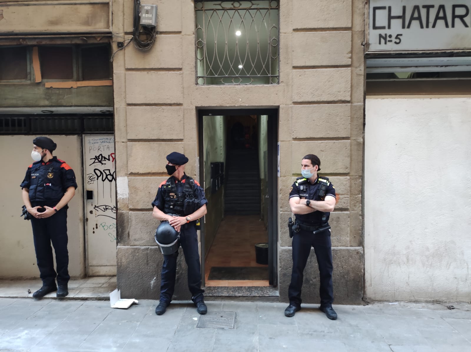 Agents dels Mossos i de la Guàrdia Urbana a la porta de l'edifici del Raval on han detingut dues persones / CME