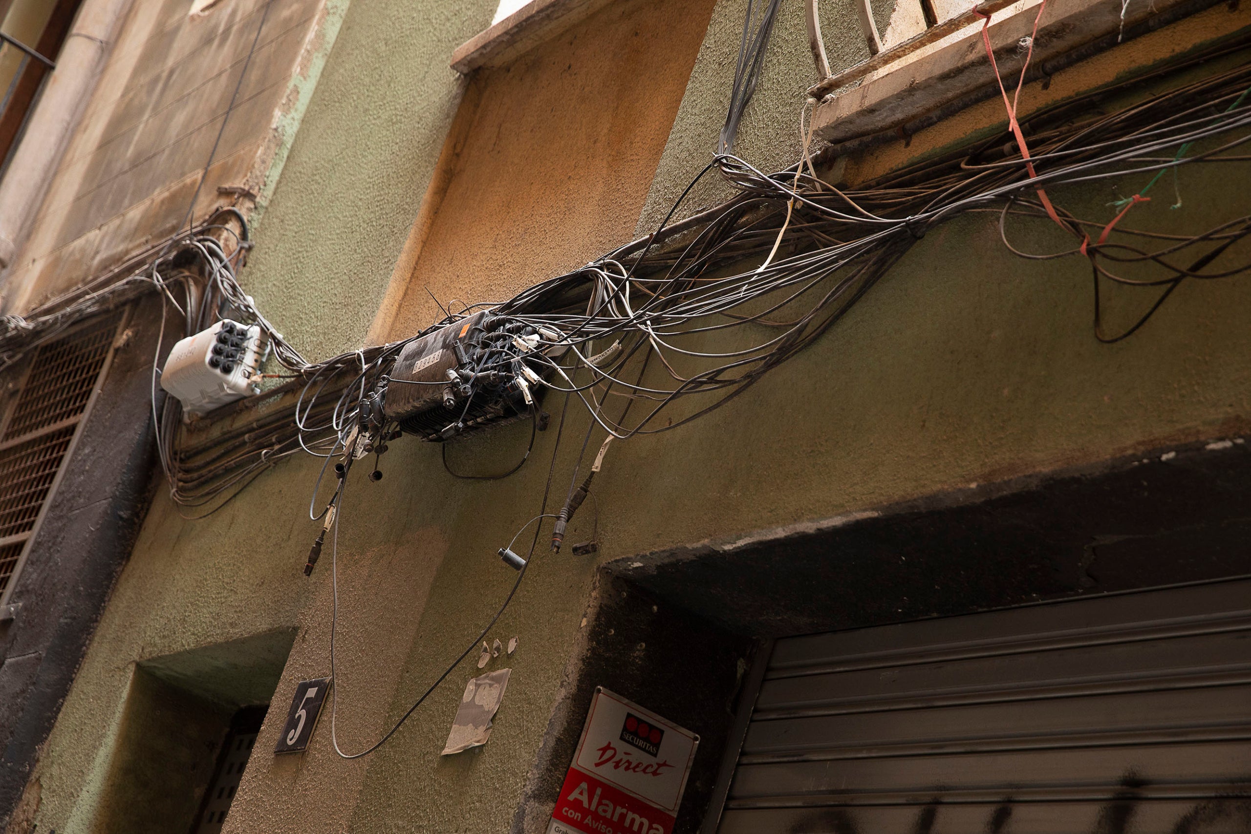 Cablejat telefònic desordenat i amb fort impacte visual en una façana d'un edifici del districte de Ciutat Vella / Jordi Play