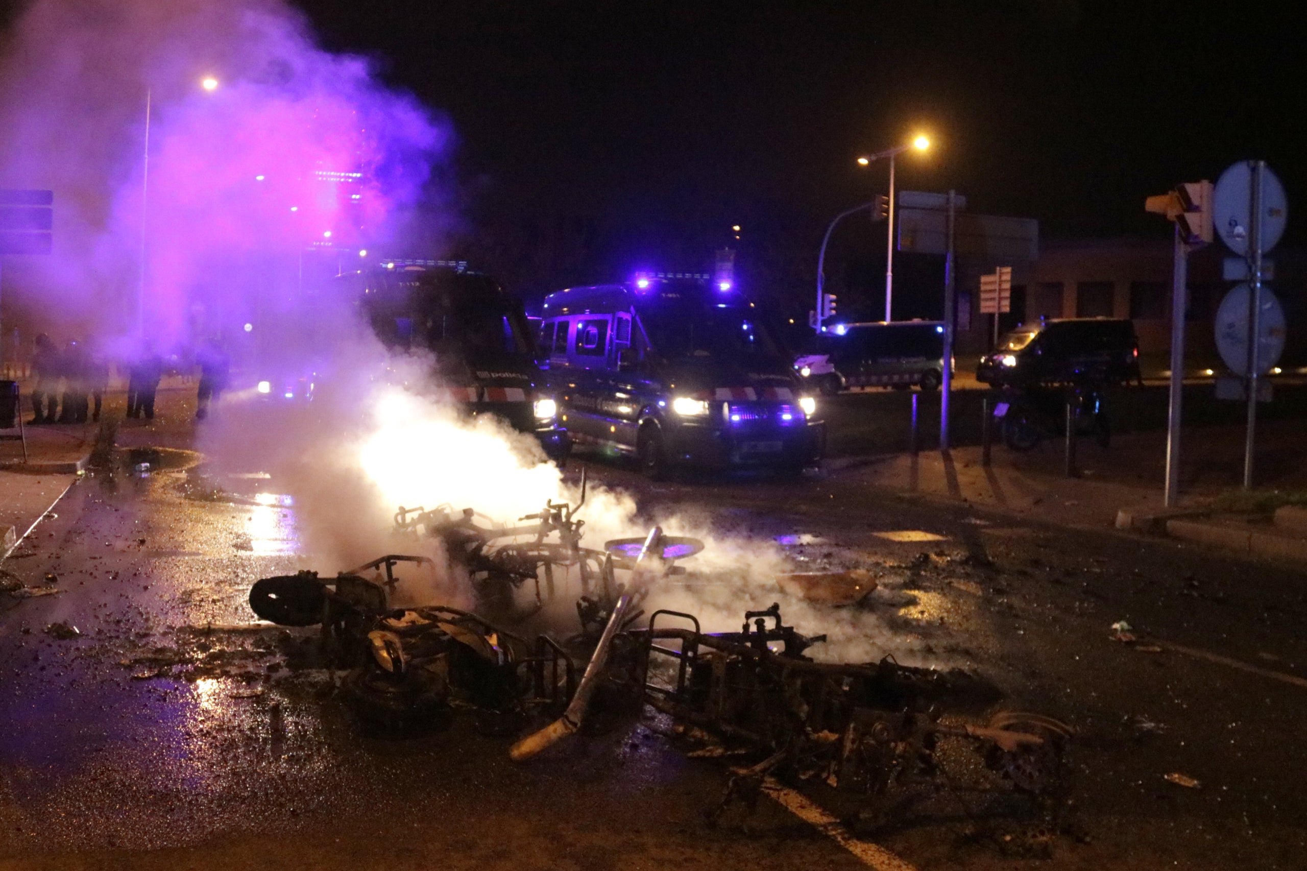 Motos cremades davant els furgons dels Mossos d'Esquadra al fons, al botellot del Bogatell / ACN