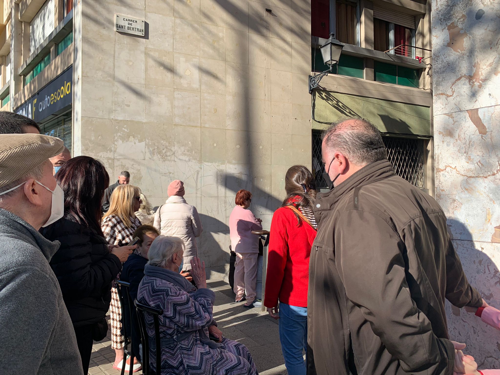 Un grup de veïns observen les tasques d'extinció d'un incendi a un local situat al número 16 del carrer de Santa Madrona aquest 1 de gener de 2022 / Sílvia Barroso