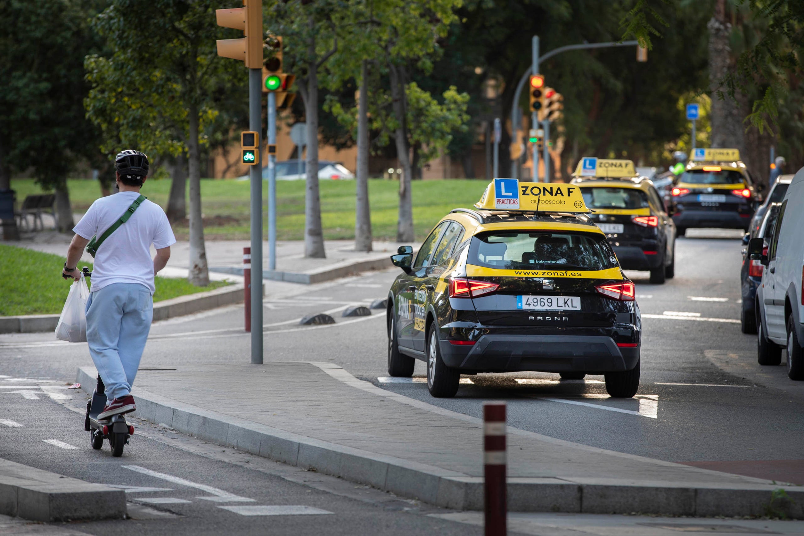 Cotxes d'autoescola pels carrers del districte de Sants-Montjuïc. Aprendre a conduir, conducció, patinet elèctric, mobilitat sostenible.