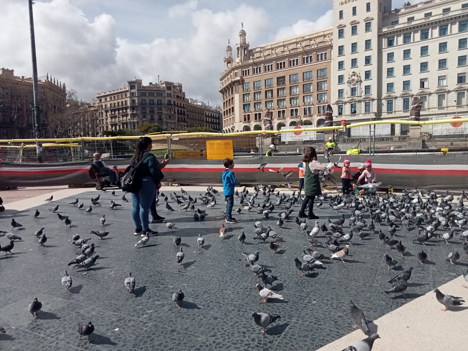 Uns turistes donen menjar a uns coloms a plaça Catalunya / A.L.