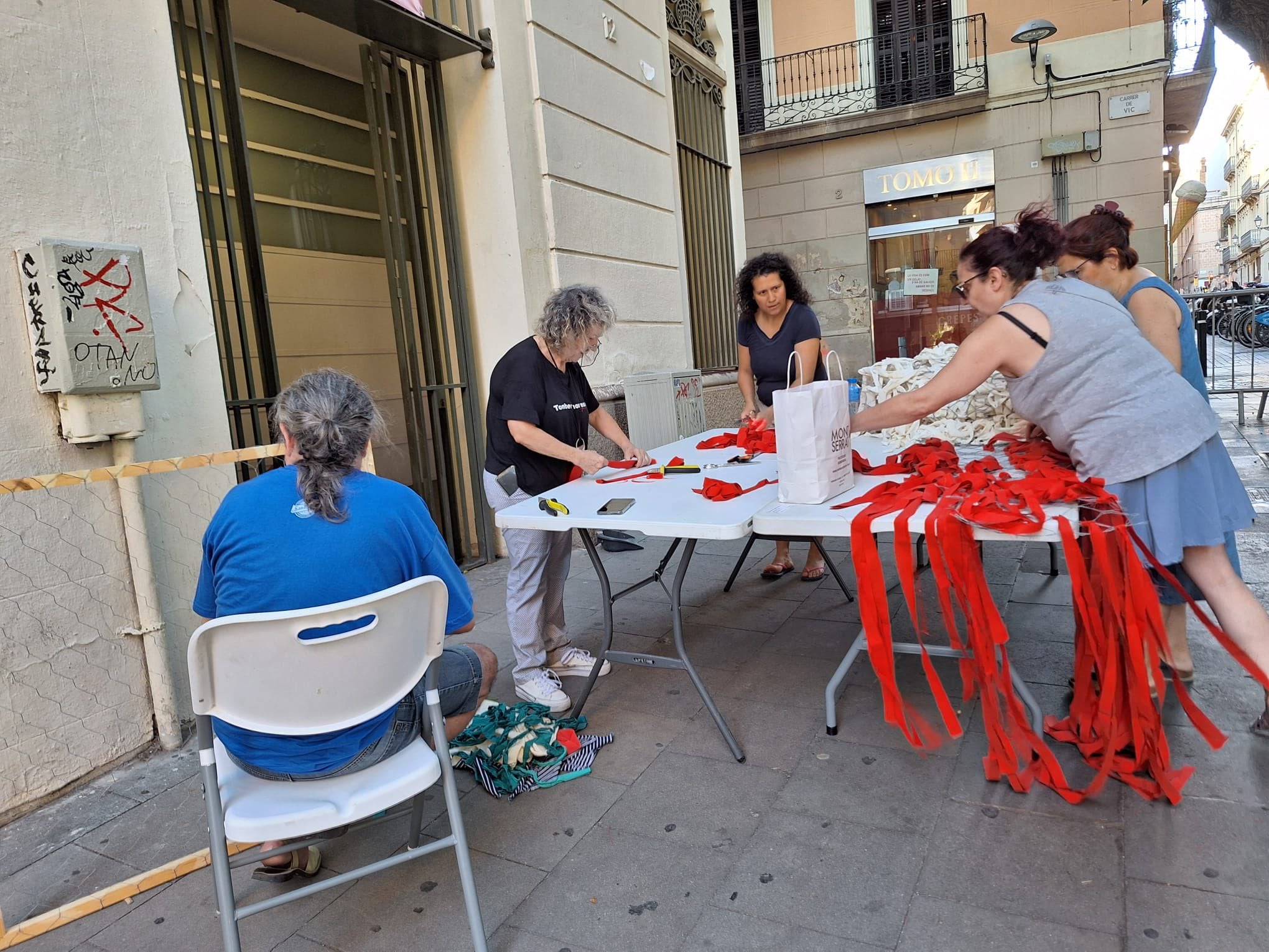 Veïnes de la placeta de Sant Miquel preparant els decoratius per la Festa Major | Twitter (@cosesdeCalaMar)