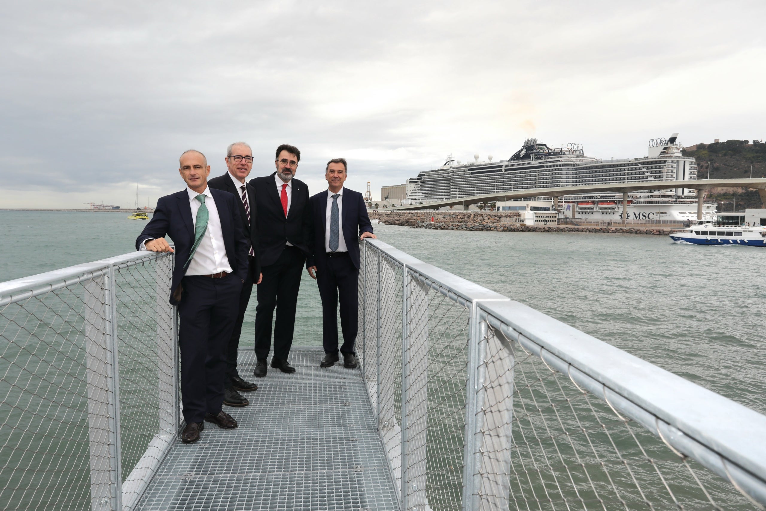 Directivos del Puerto de Barcelona y de Marina Vela acompañados por los responsables de la construcción y tematización de los nuevos espacios, con el Edificio Mirador al fondo | El Puerto