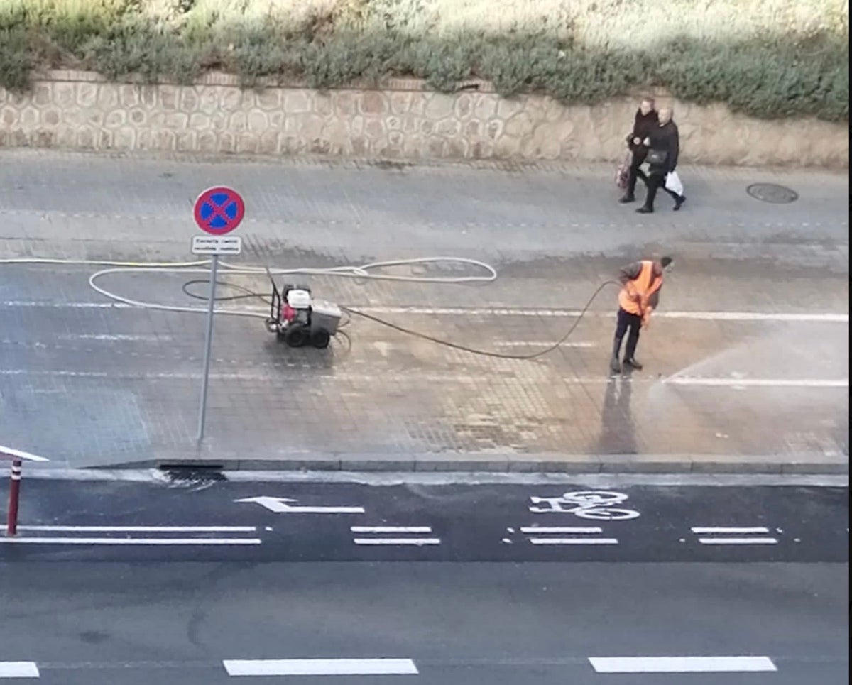  operaris esborren pintura d’un carril bici a la vorera amb aigua a pressió. X de Jordi Coronas 