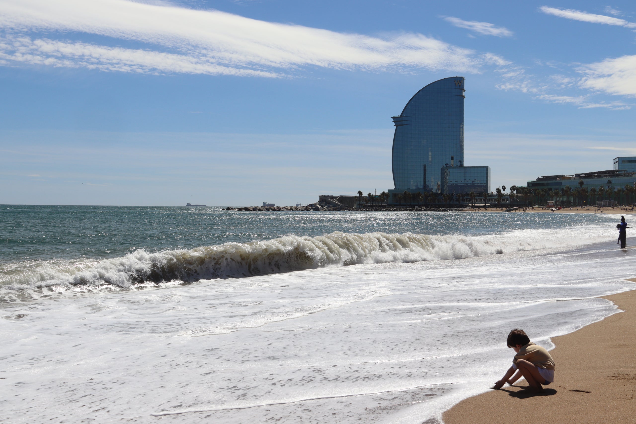 Onades a la platja de Sant Sebastià amb l’Hotel Vela de fons després del temporal / ACN