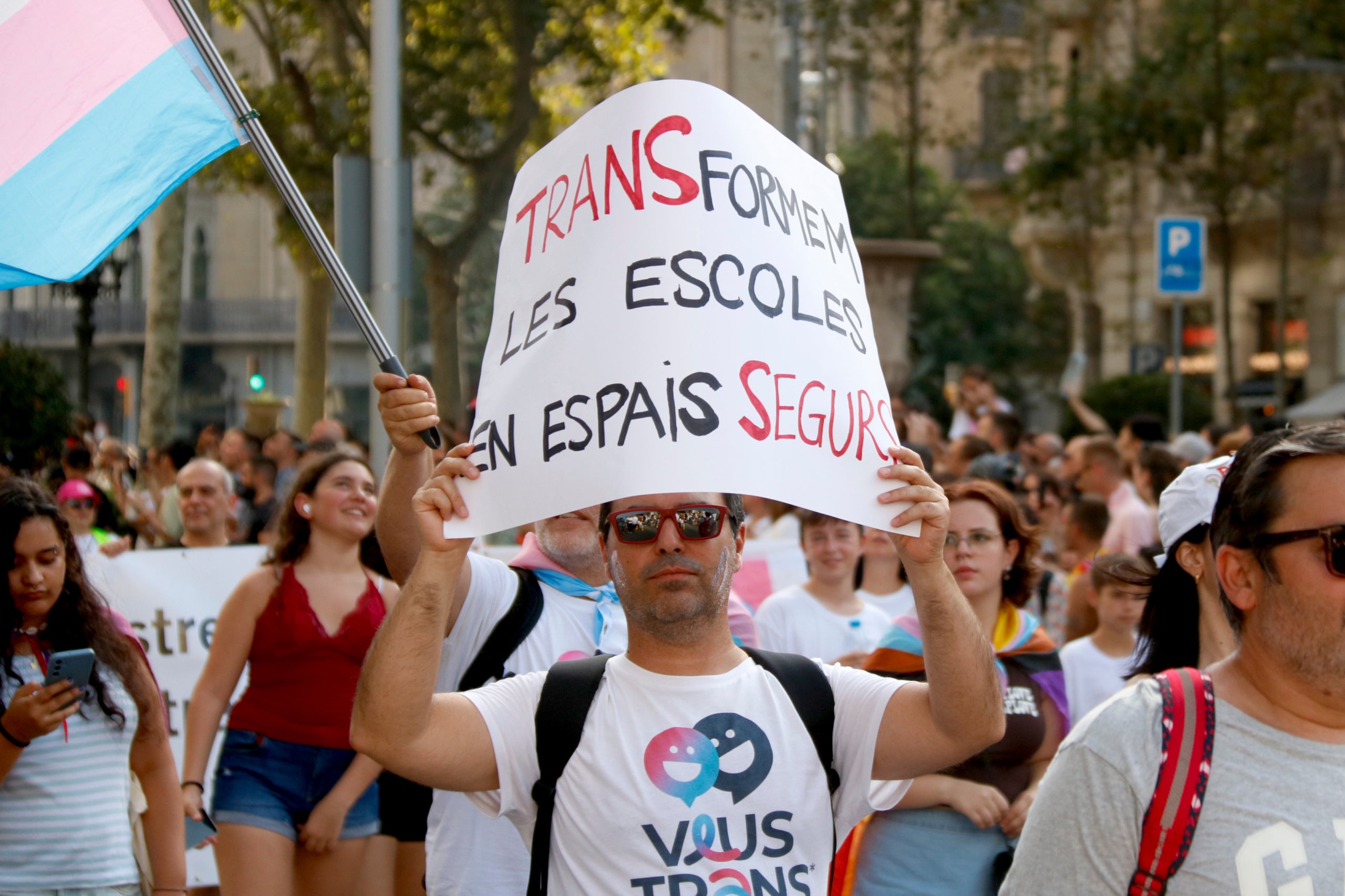 Un manifestant en la marxa del Pride amb una pancarta a favor de transformar les escoles / ACN