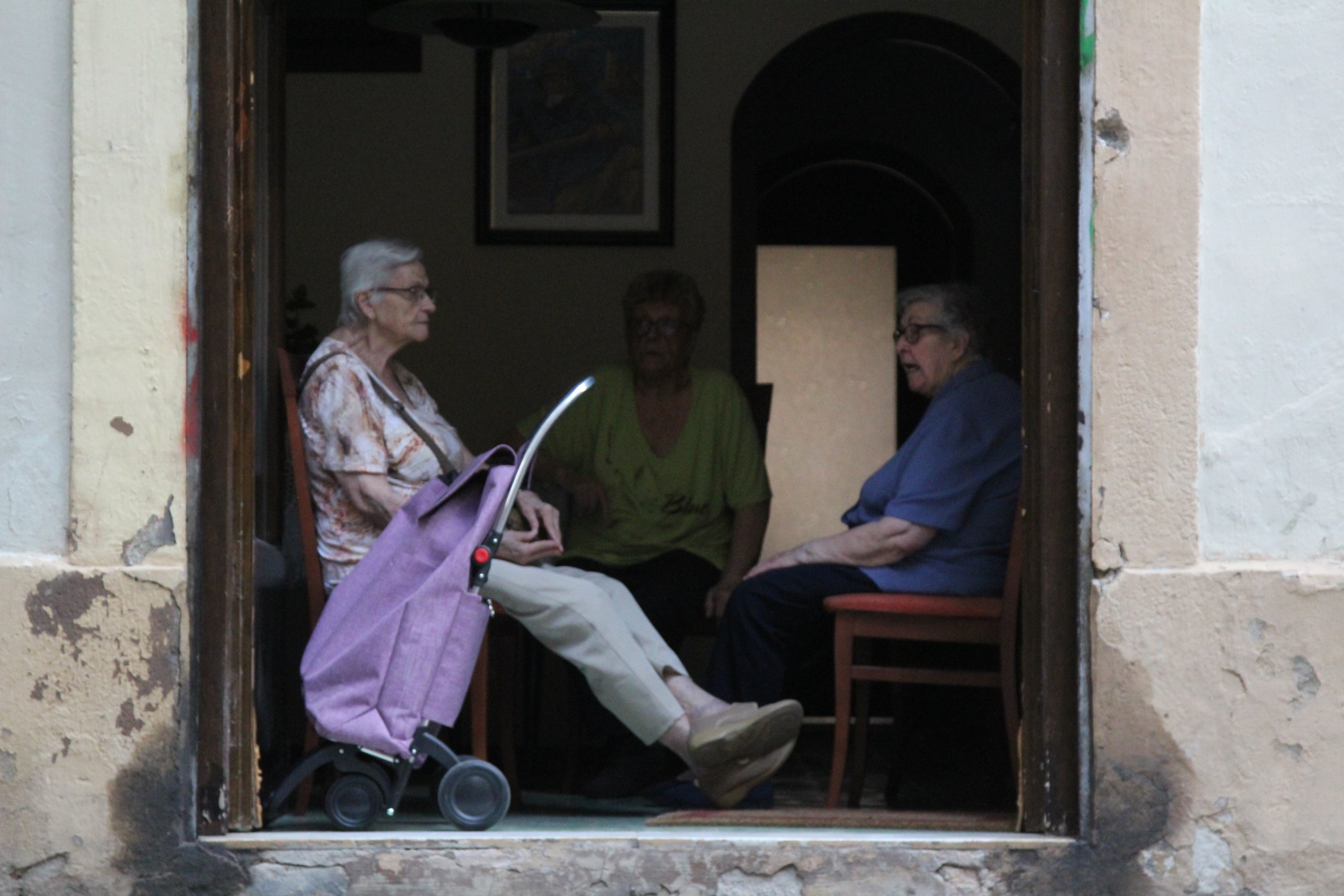 Tres àvies conversen amb les portes de casa obertes en un dels carrers guarnits de Sants / A.R.