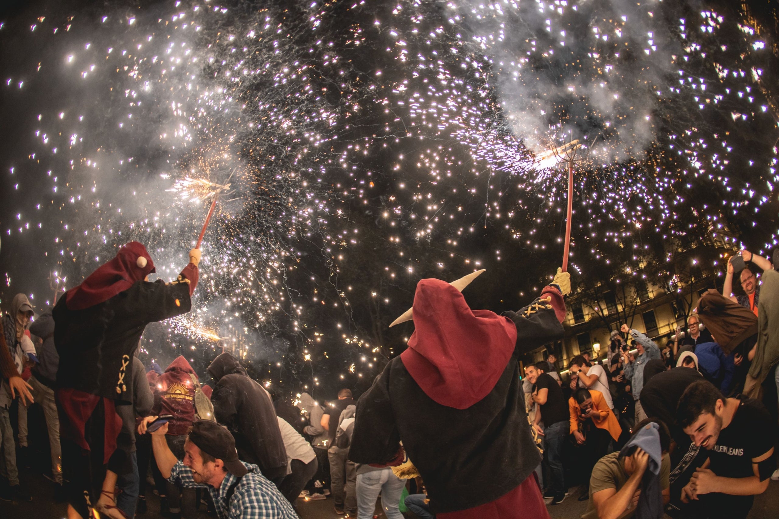 Correfoc de la Mercè 2022, amb el públic més agosarat cobrint-se davant la pluja de guspires que surten de les carretilles dels Diables / Ajuntament