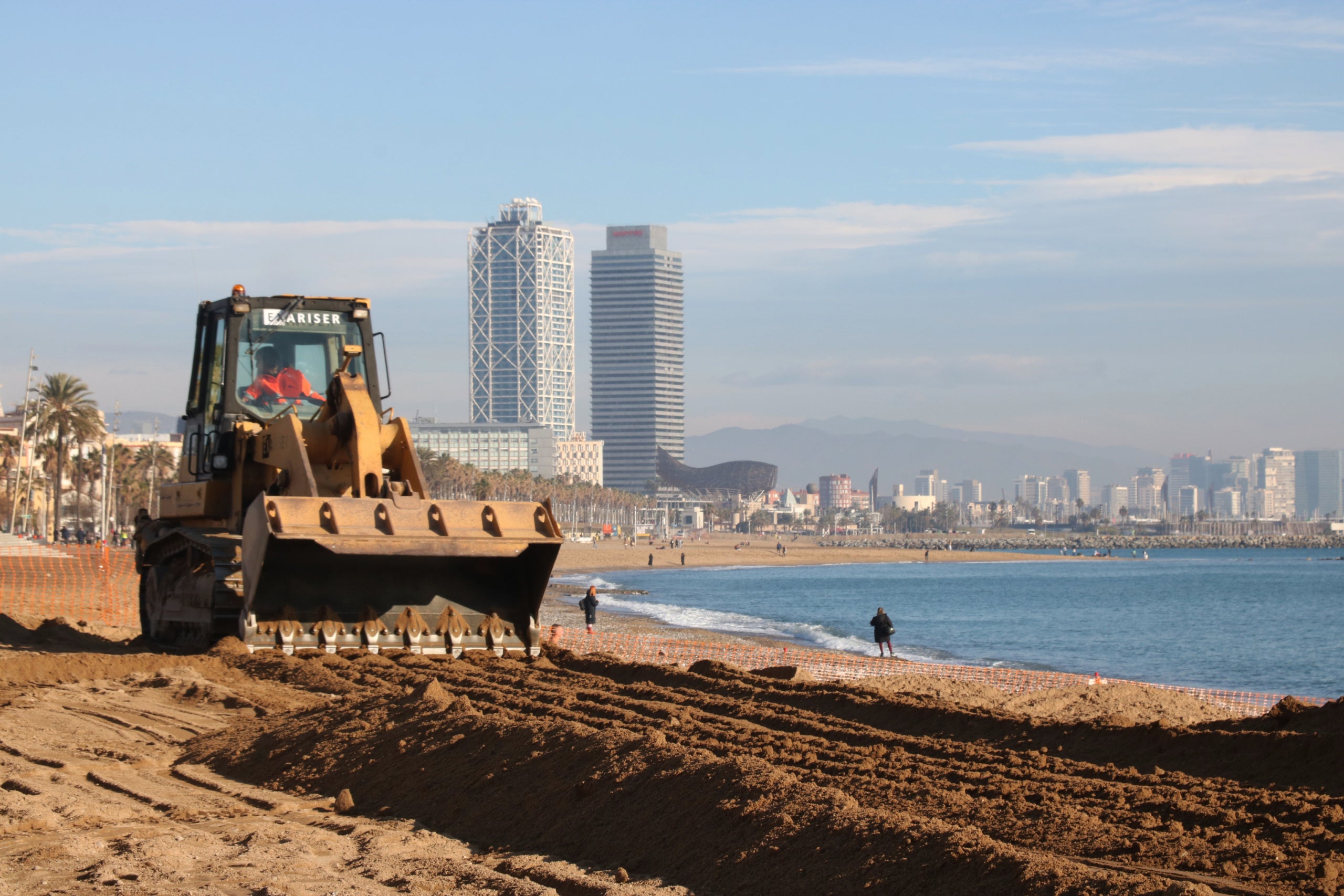 Una excavadora aplanant la sorra a la platja de Sant Sebastià / Norma Vidal (ACN)