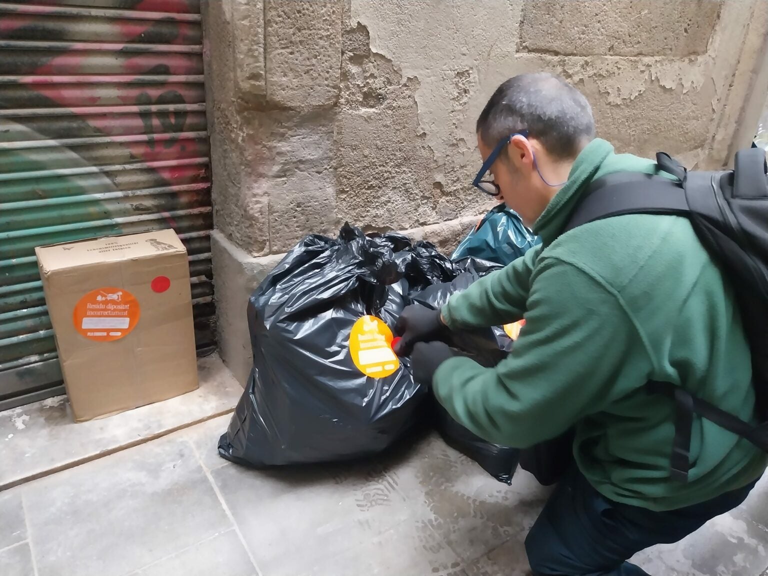 Un agent cívic col·loca un adhesiu en una bossa d'escombraries / Ajuntament de Barcelona