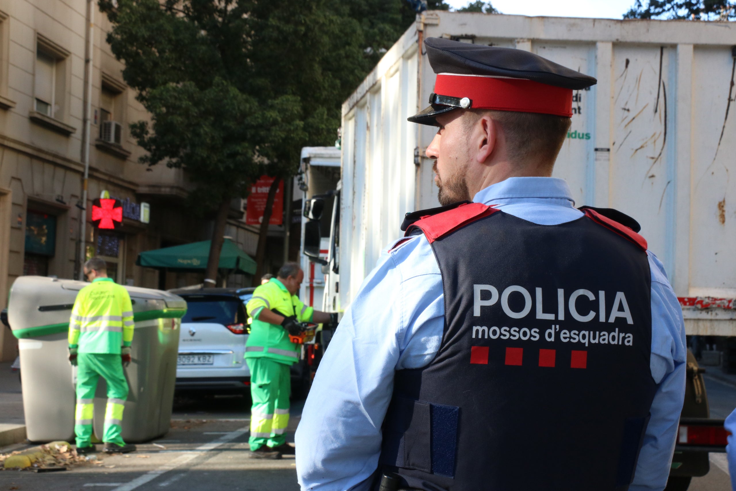 Imatge d'un mosso vigilant les tasques dels serveis de neteja de l'Ajuntament de Barcelona mentre retiren el contenidor on s'ha localitzat el cos / ACN