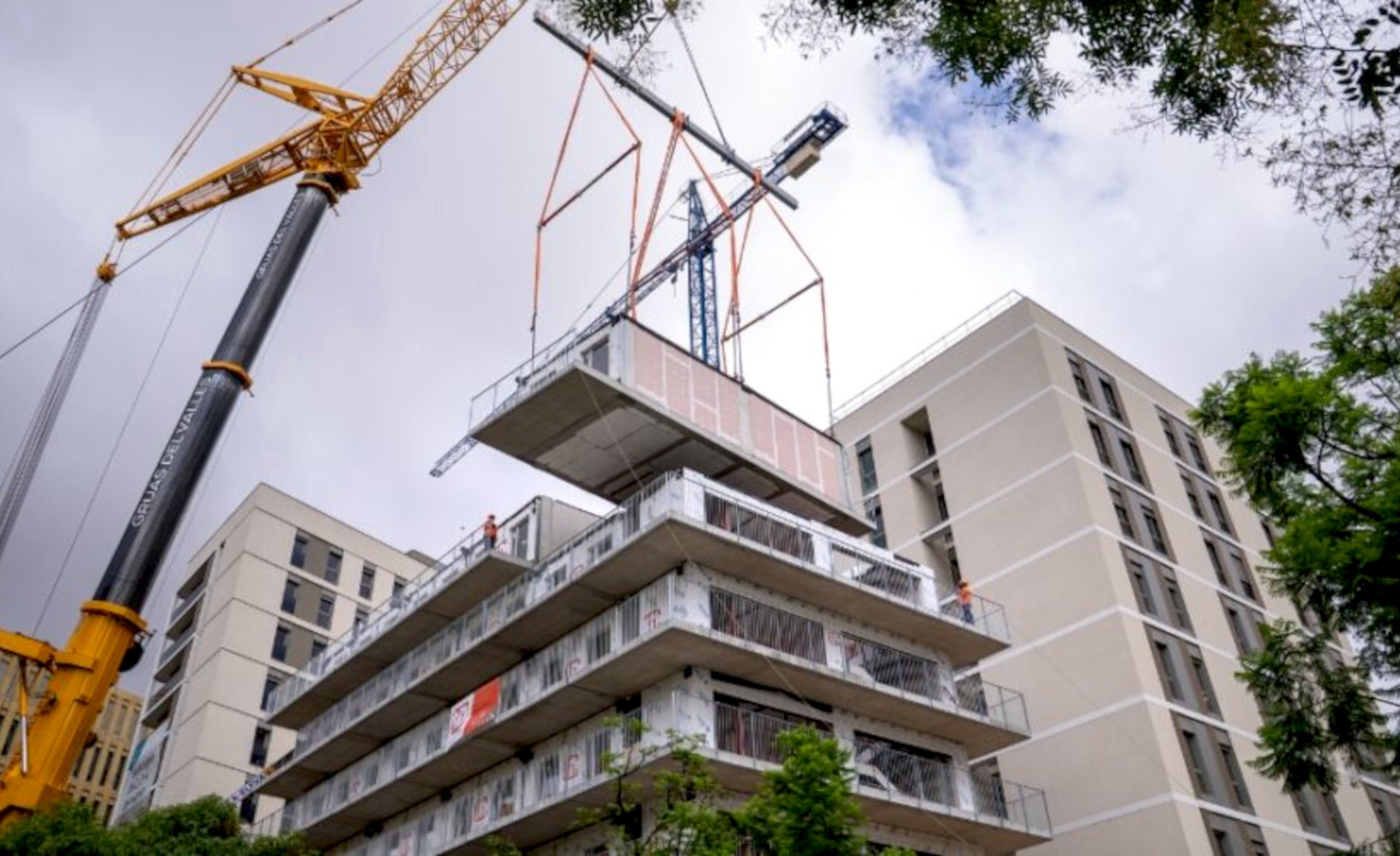 Una grua aixeca un dels blocs prefabricats per construir un edifici de pisos a la Bordeta. | Ajuntament de Barcelona (ACN)