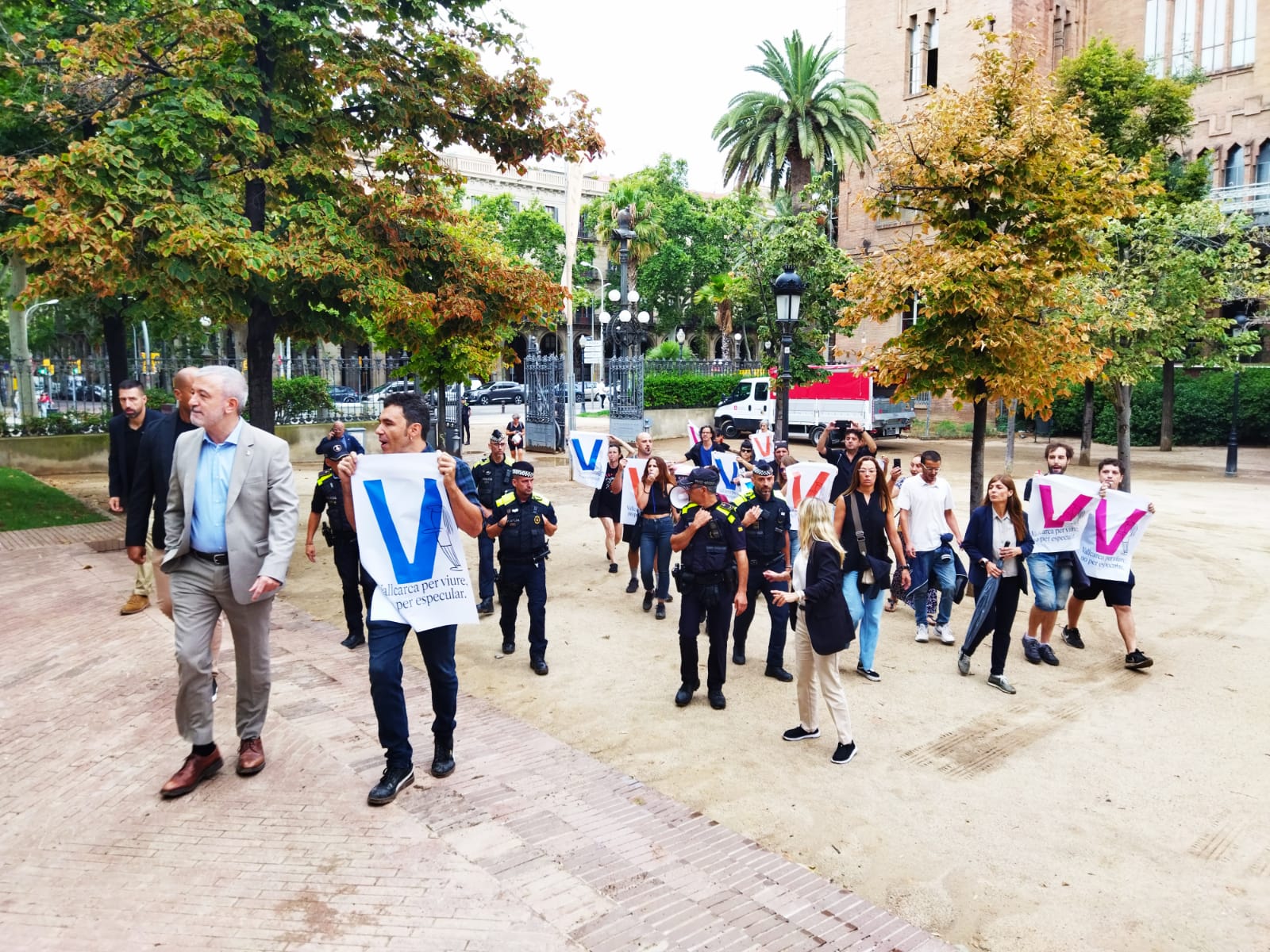 Jaume Collboni, a l'entrada de l'acte de la Mercè, a la Ciutadella, amb manifestants al darrere / Jordi Subirana