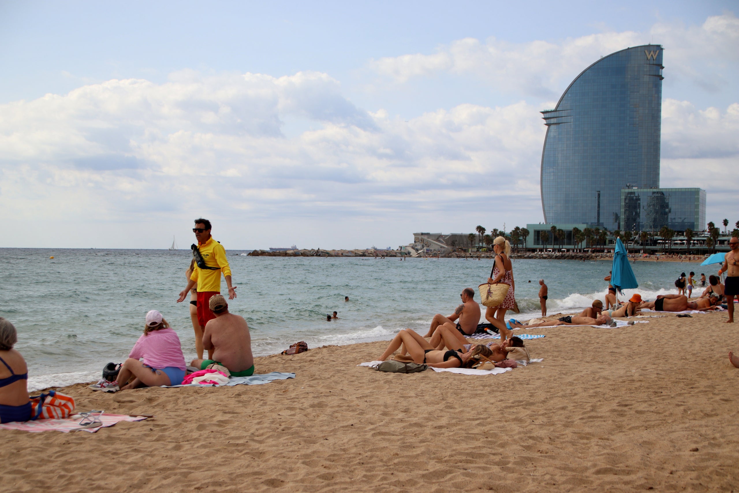 Un socorrista parla amb dues persones a la platja de Sant Sebastià / ACN
