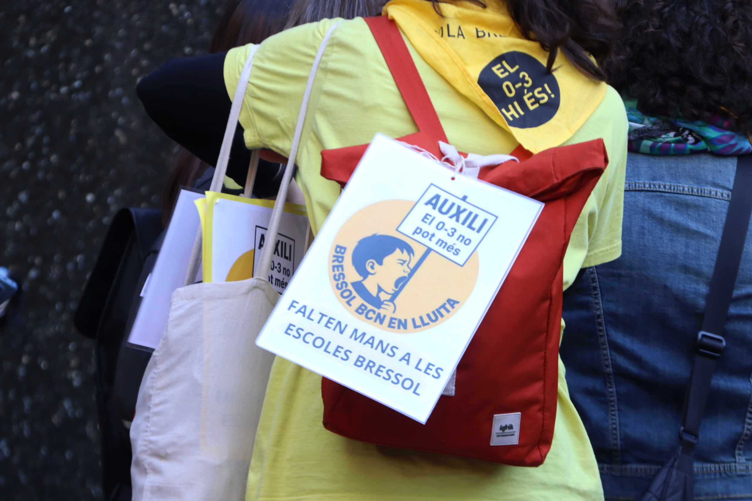 Una treballadora porta un cartell penjat a la motxilla amb l'advertència